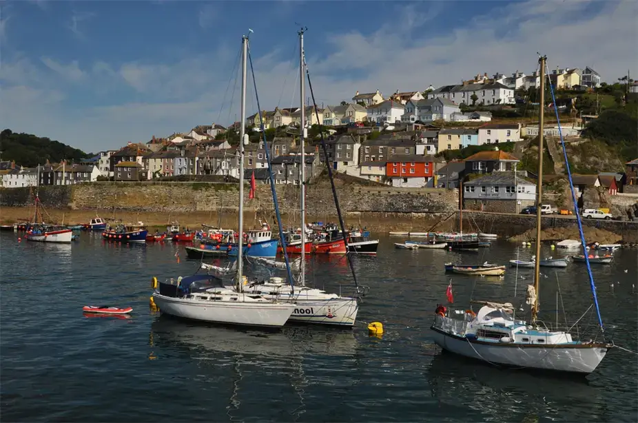 Yachts moored in Mevagissey harbour with houses on the hillside
