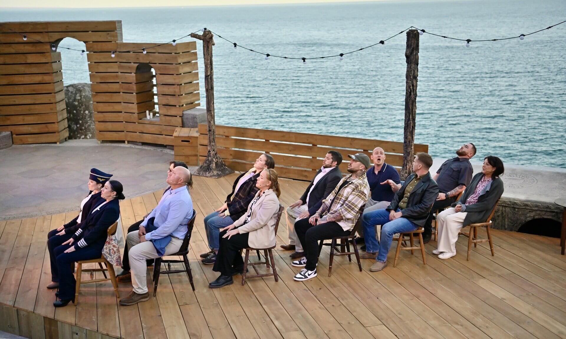 Come From Away cast seated on the Minack stage with the Atlantic behind
