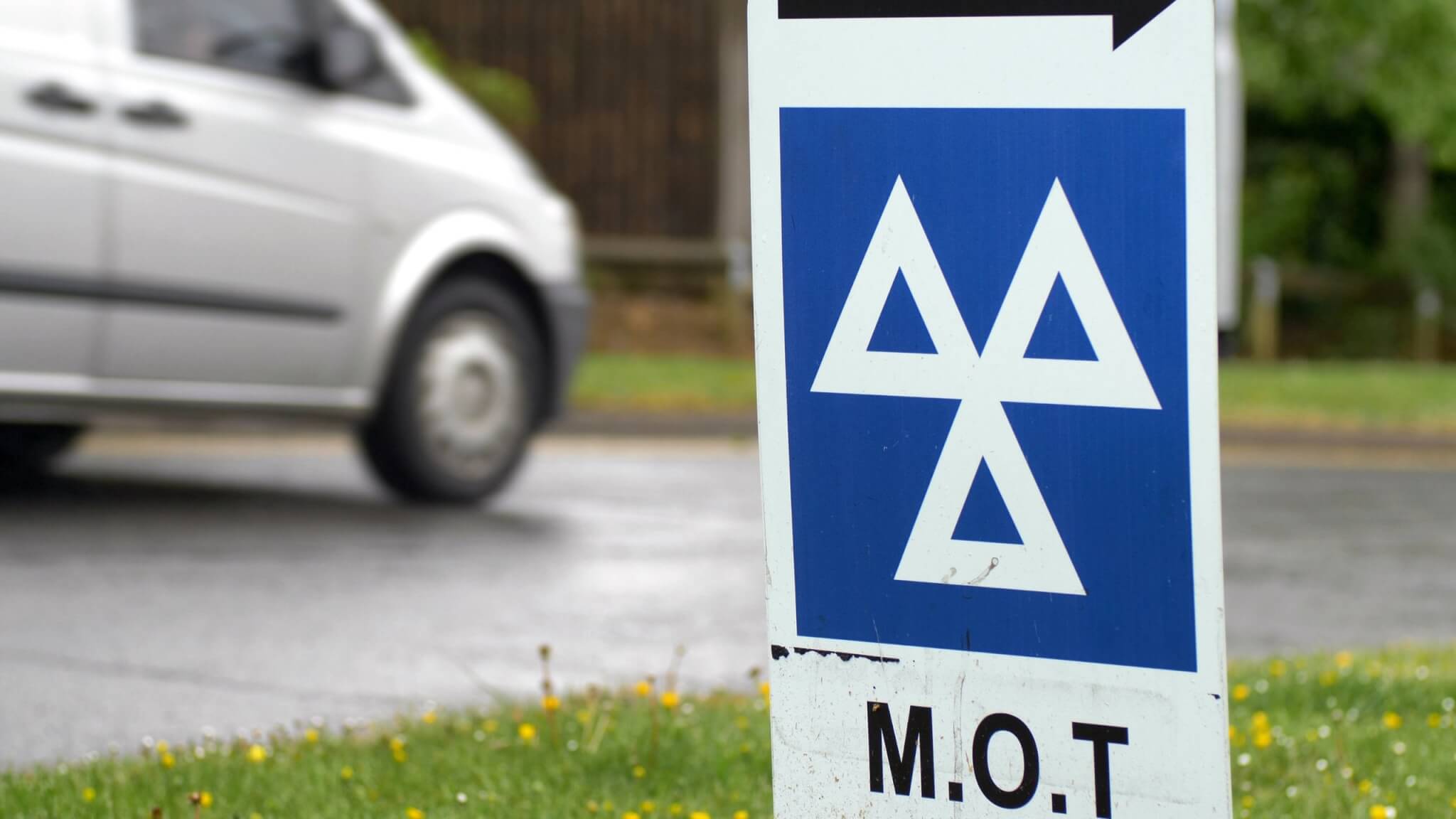 MOT test centre sign beside a road with a van passing