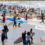 Hundreds of surfers carrying boards into the sea at an Earthwave event