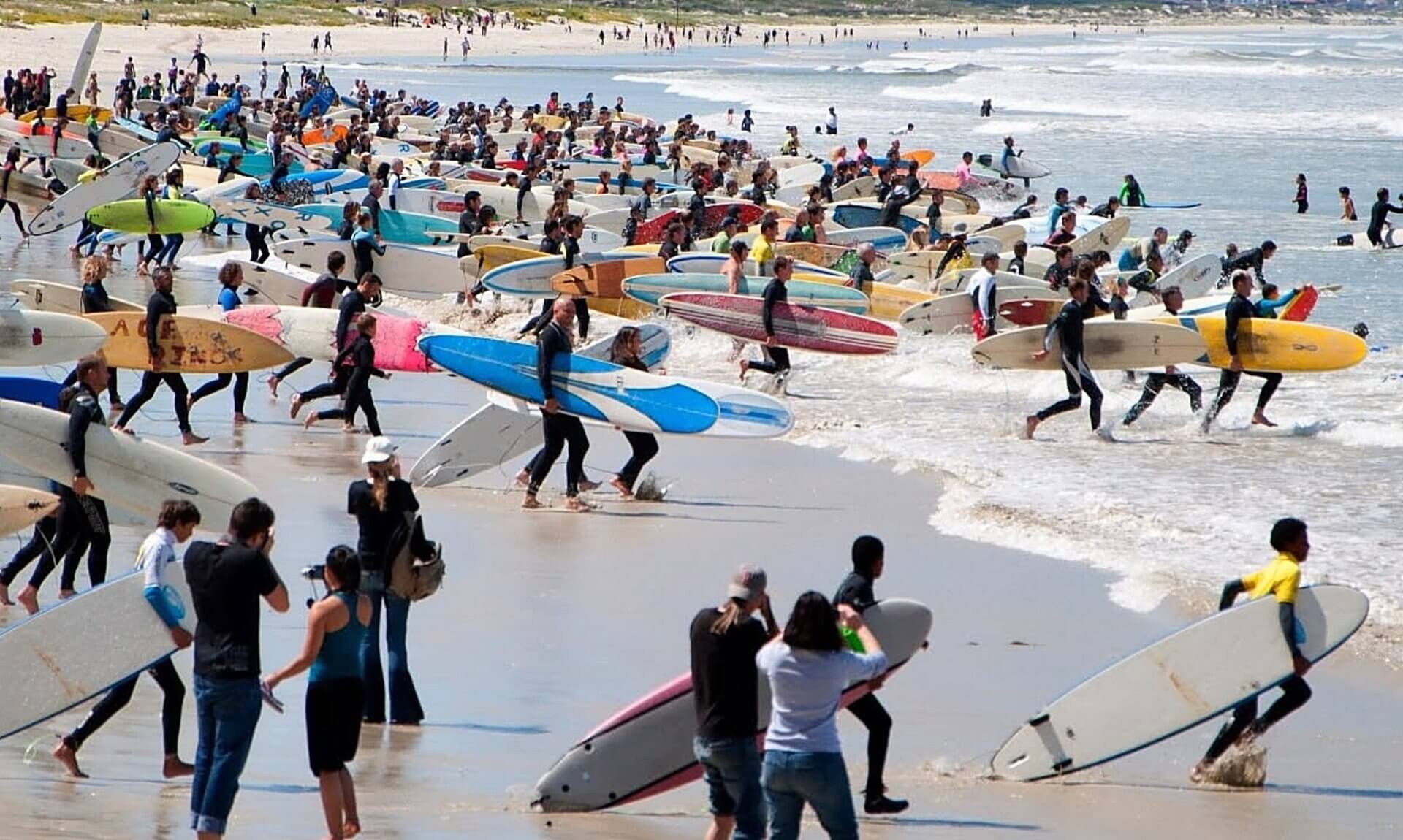 Hundreds of surfers carrying boards into the sea at an Earthwave event