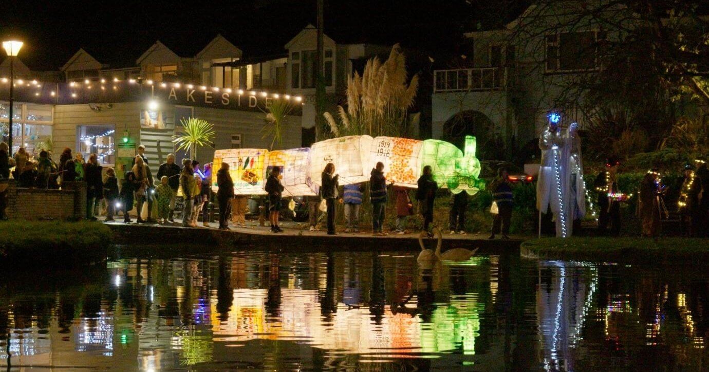 Illuminated lanterns carried past the lake in Trenance Valley, Newquay
