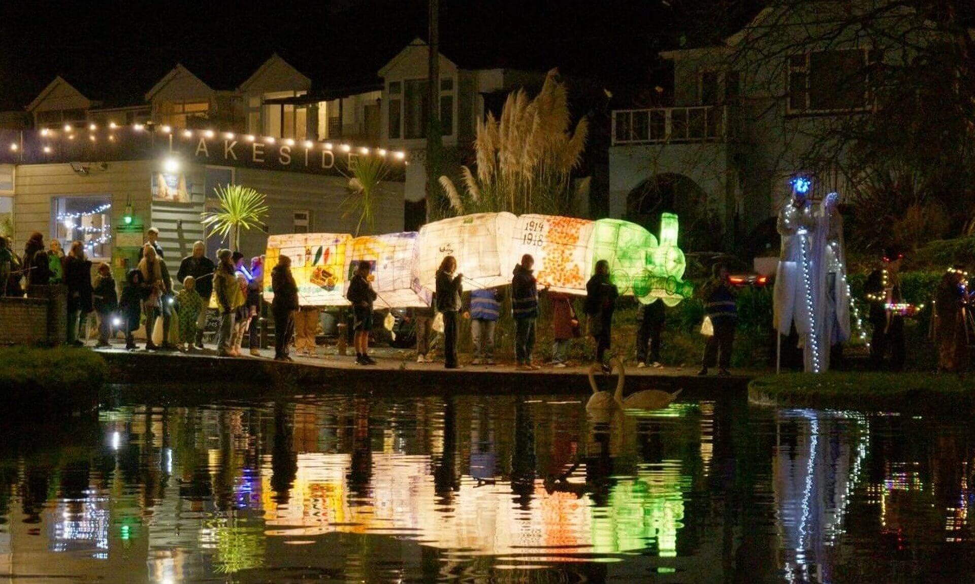Illuminated lanterns carried past the lake in Trenance Valley, Newquay