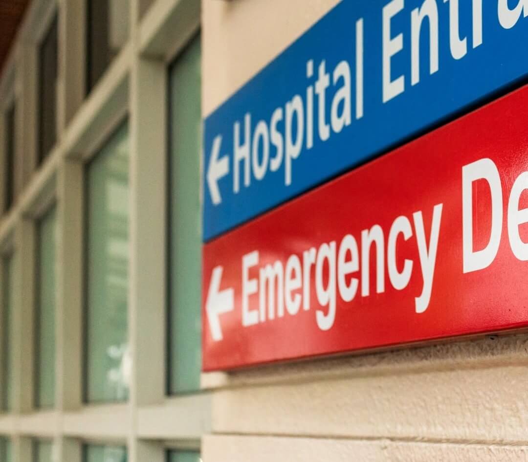 Hospital entrance and emergency department signs on a hospital wall