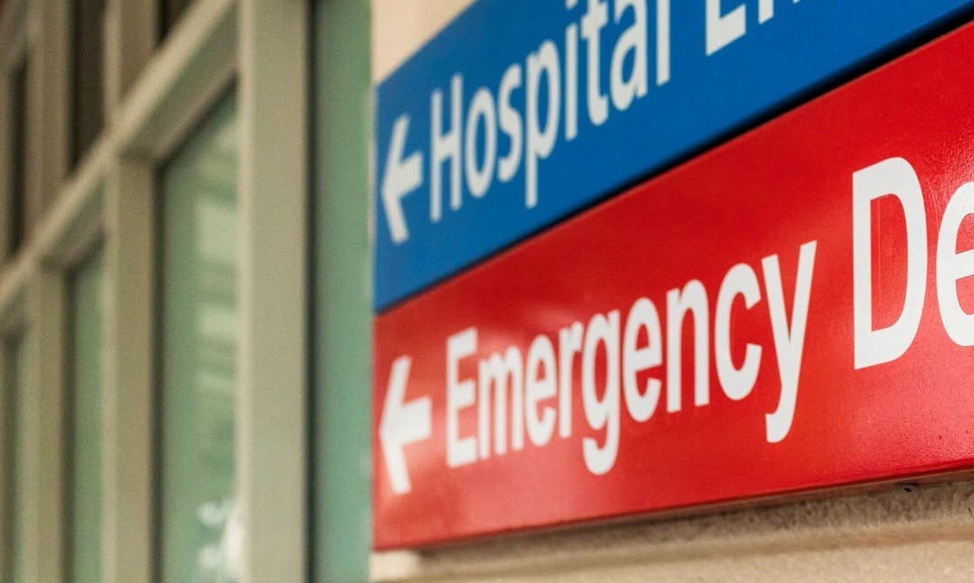 Hospital entrance and emergency department signs on a hospital wall