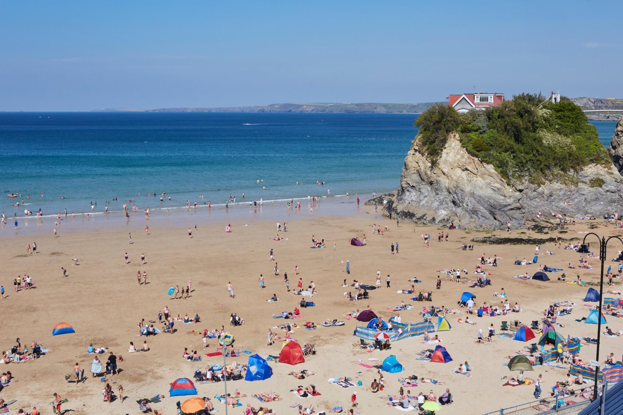 Busy summer day on Towan Beach in Newquay with The Island and its house on the rock