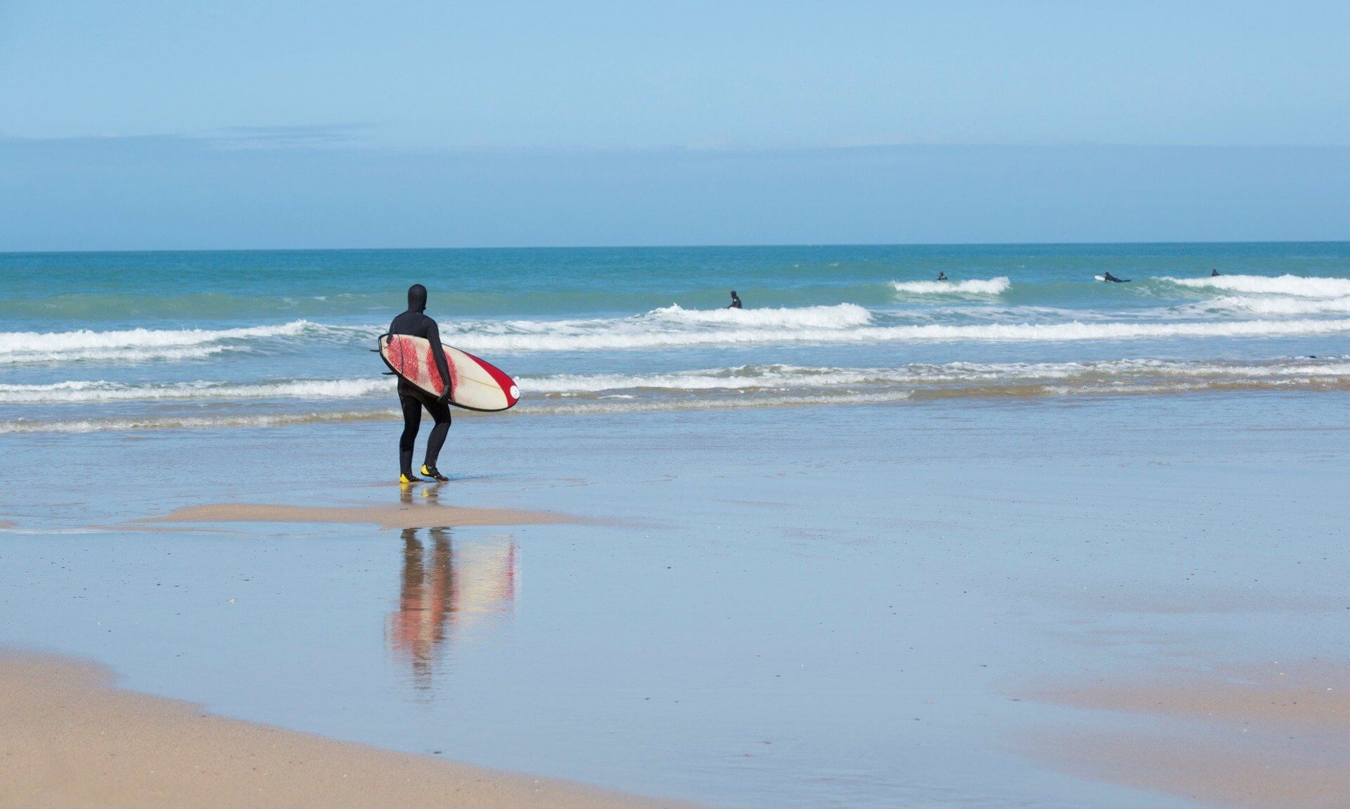 A surfer carrying a board walks towards the sea