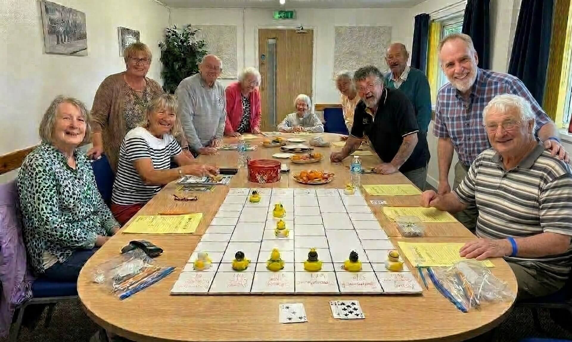 Oddfellows members smiling around a table set up for a duck race game