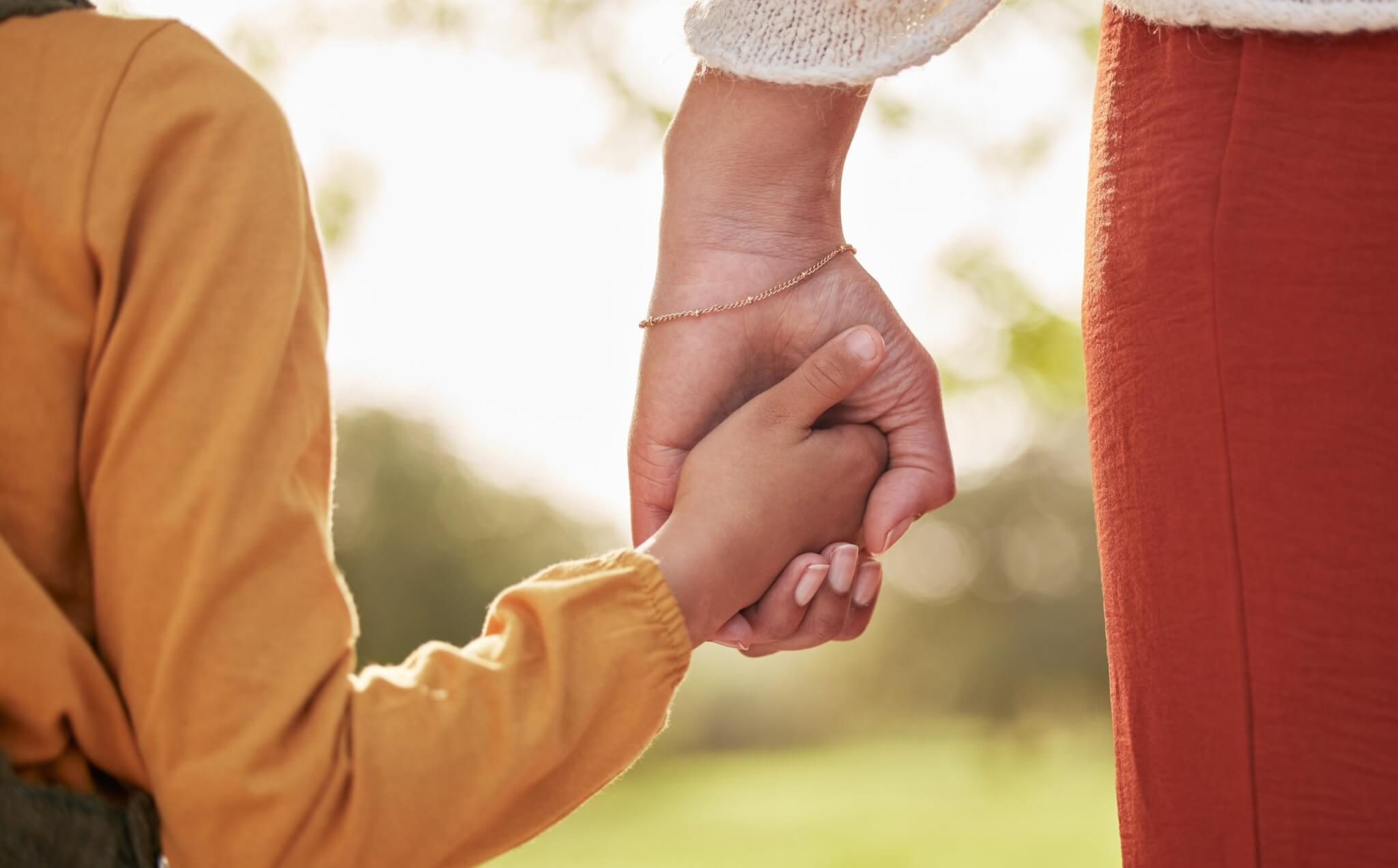 Parent holding a child's hand outdoors