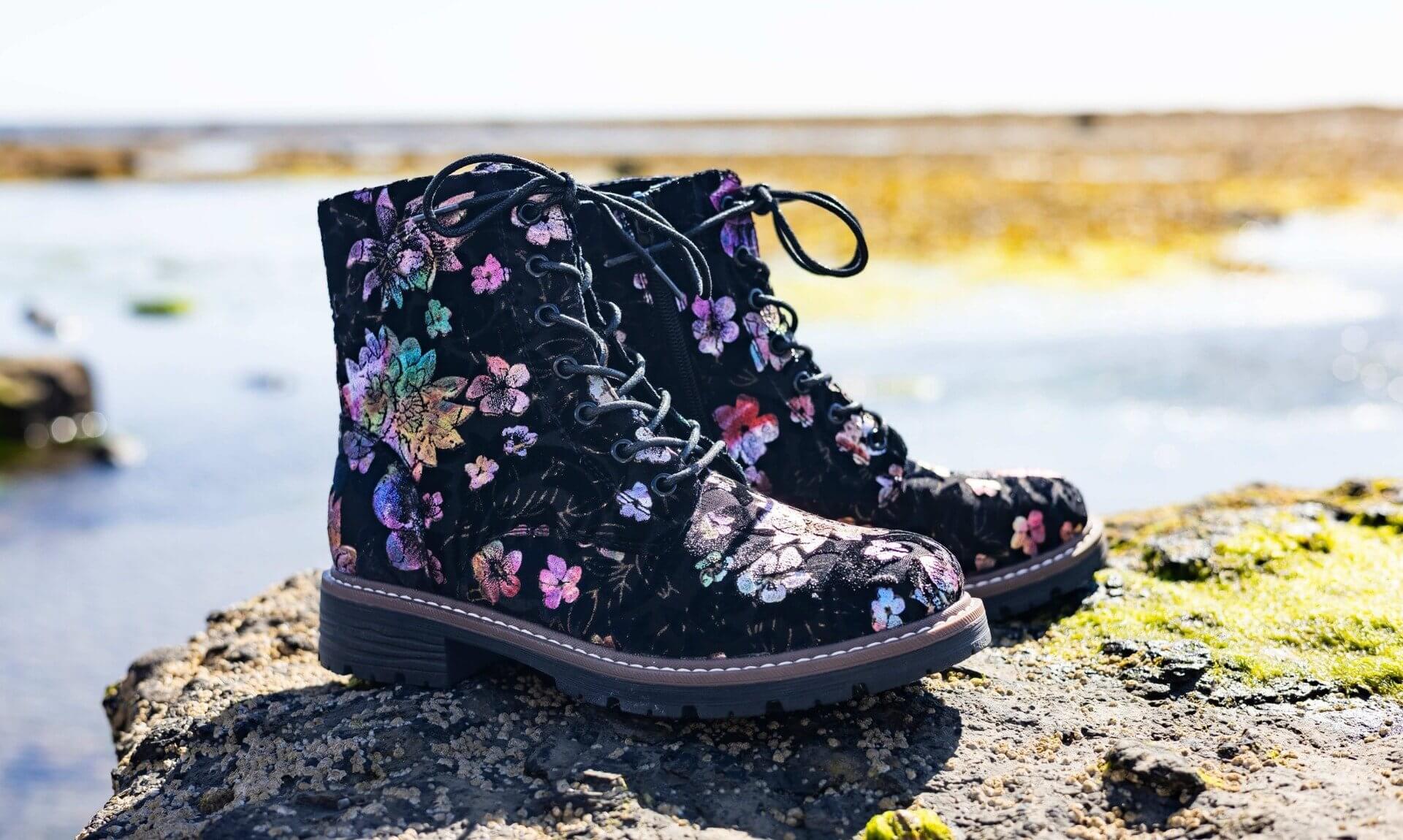 Black floral lace-up Pavers boots on a rock beside the sea