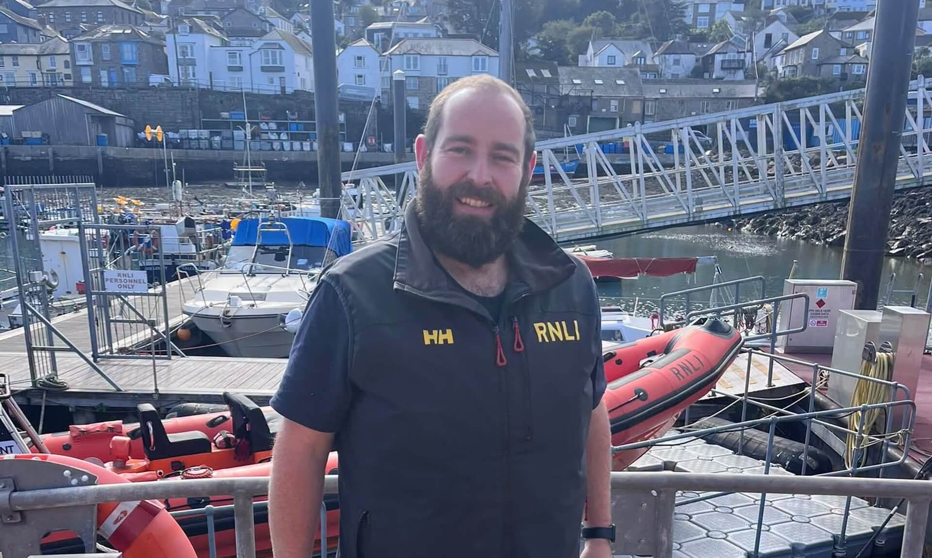 Penlee Lifeboat volunteer in RNLI kit standing on the deck of the lifeboat in the harbour