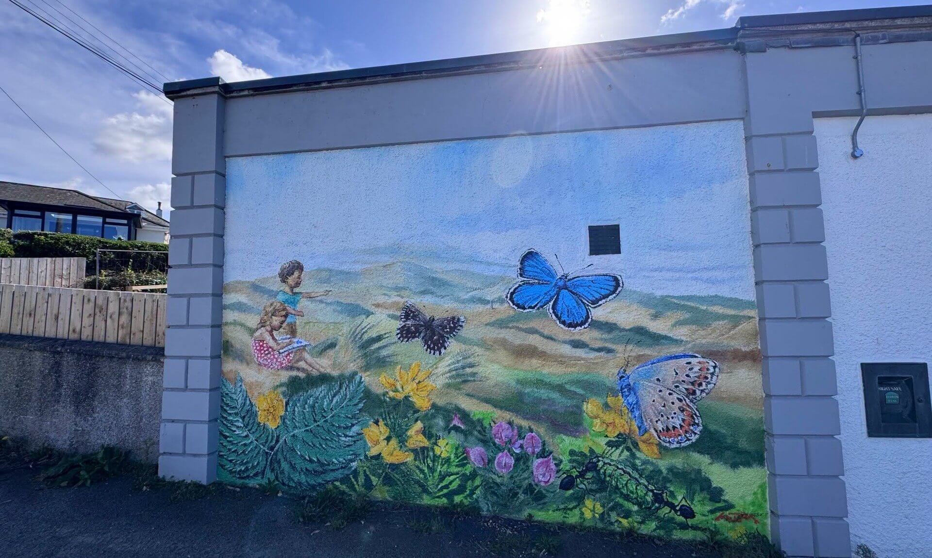 Mural of butterflies, wildflowers and two children on the wall of Perranporth Community Library
