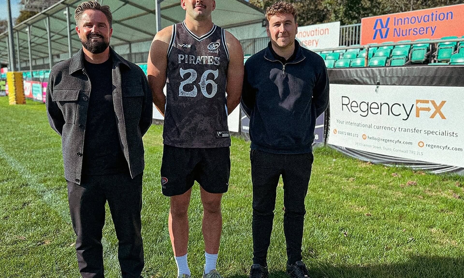 Josh Radcliffe of the Cornish Pirates with Andy Dyer and Sam Harratt pitchside by a Regency FX banner