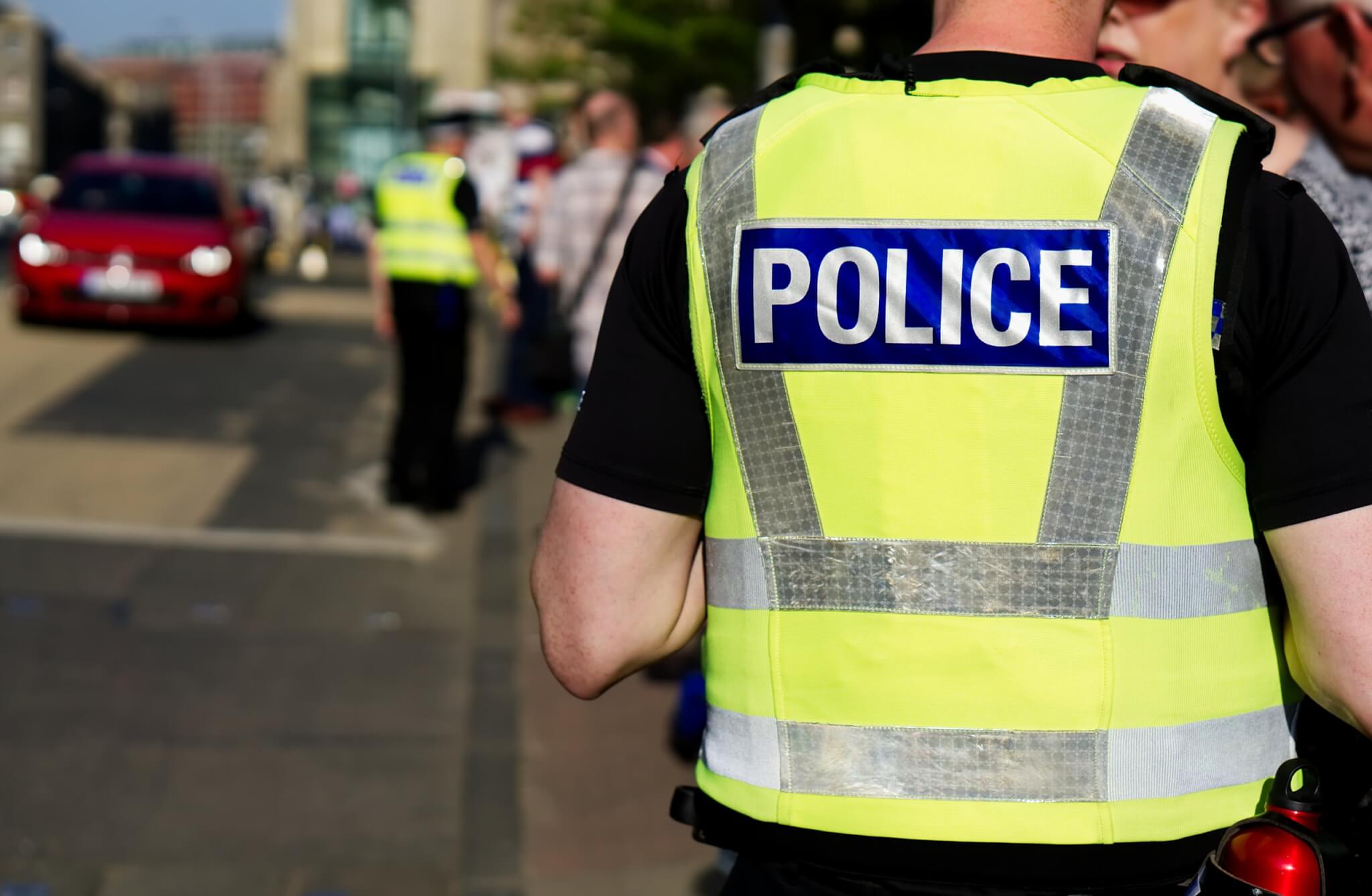 Police officer in a hi-vis vest seen from behind on a busy street