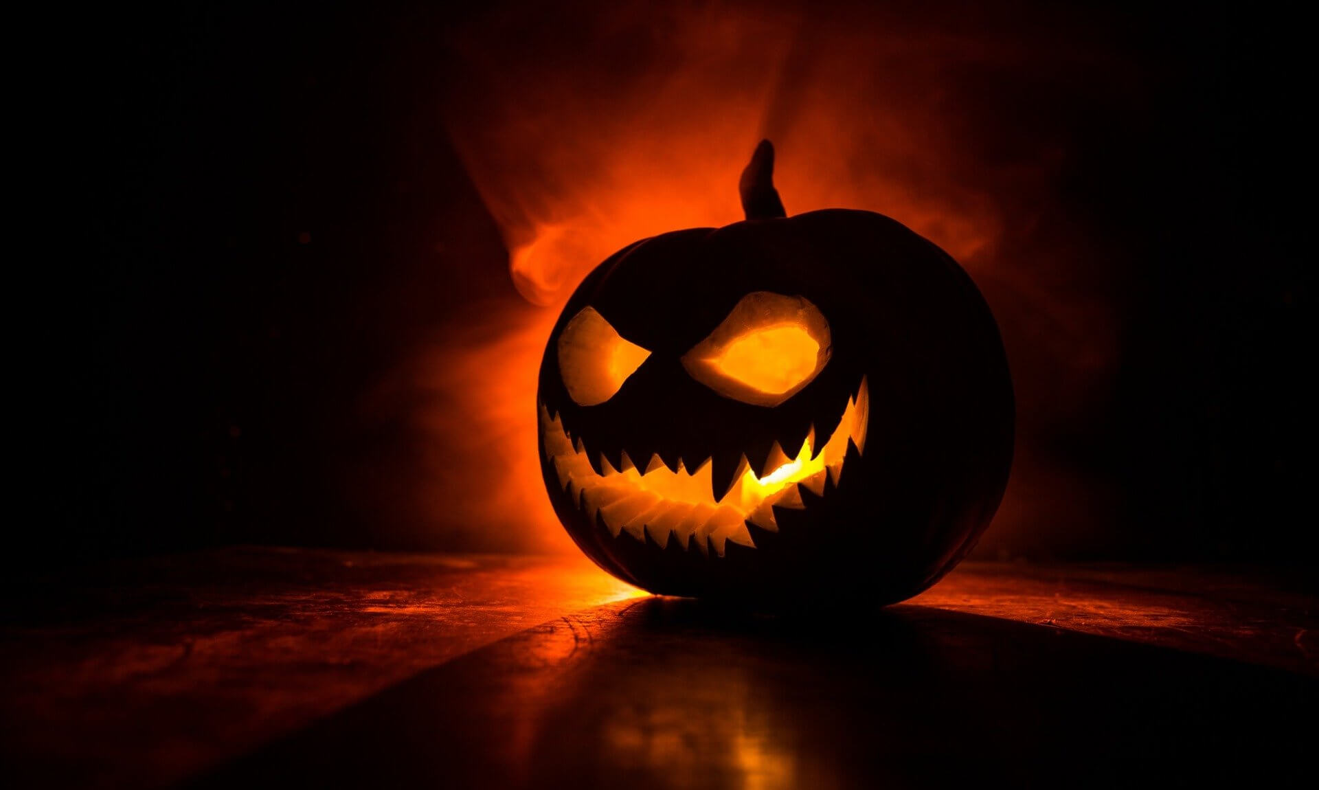 A carved jack-o-lantern pumpkin glowing orange in the dark
