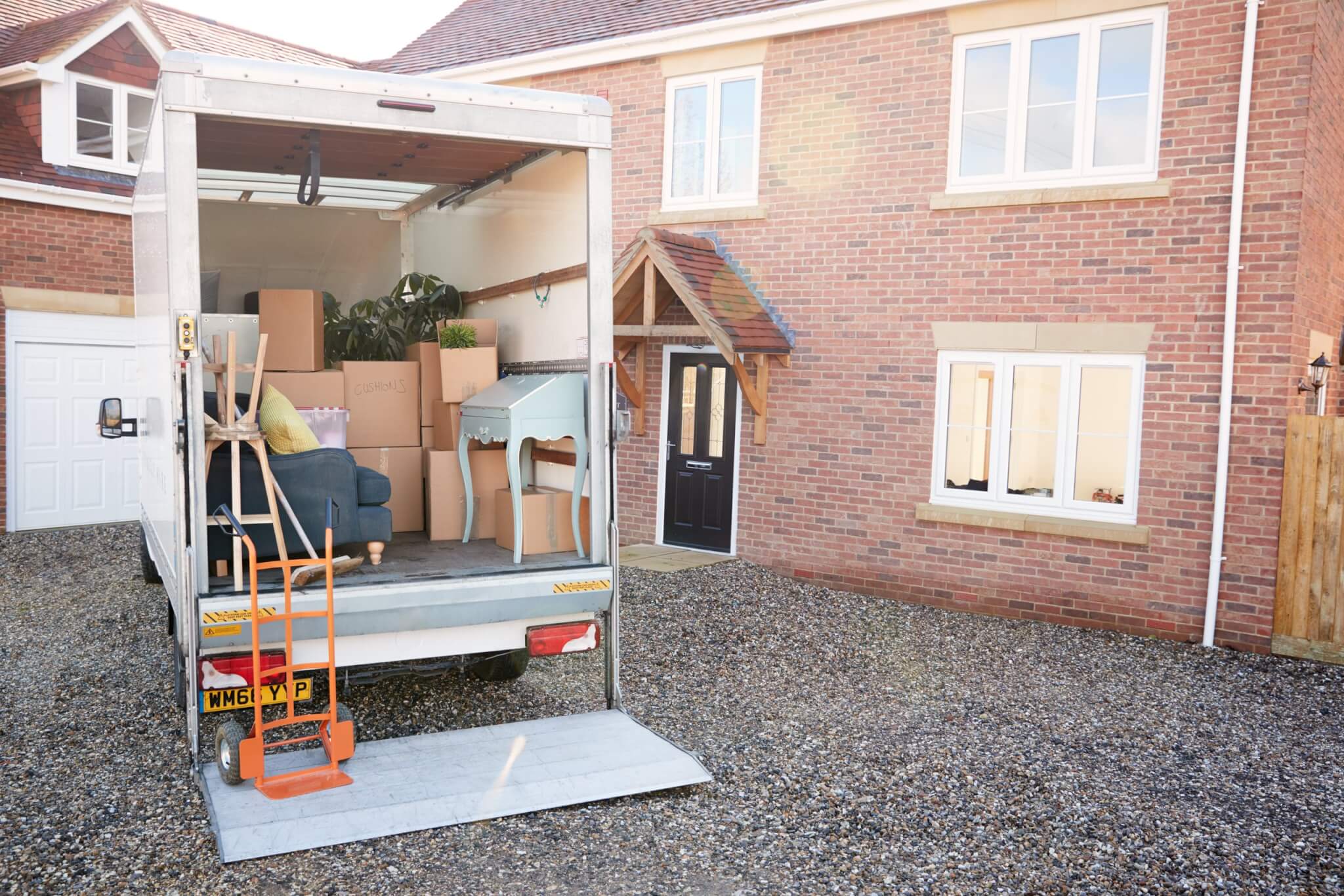 Removal van loaded with boxes and furniture outside a brick house