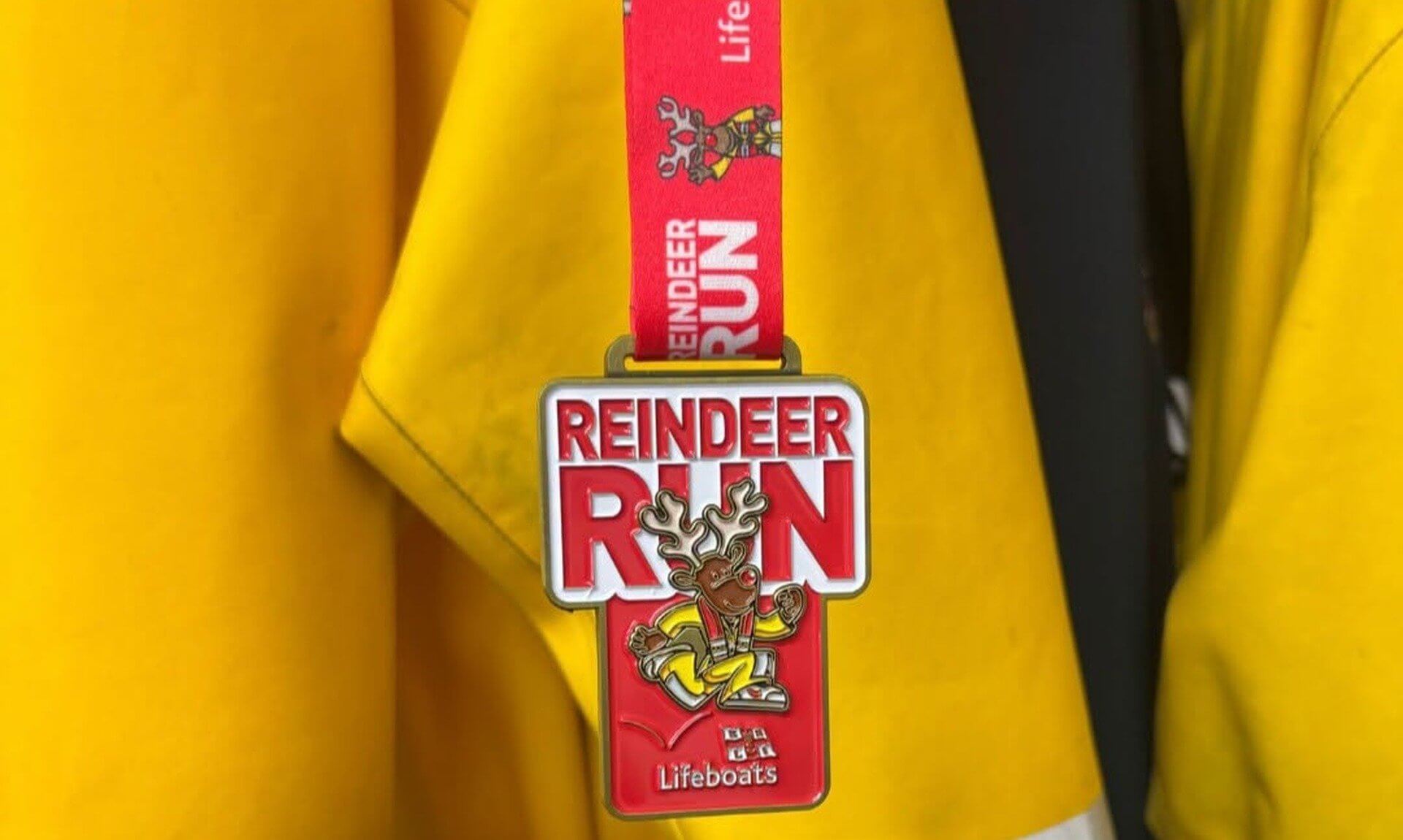 RNLI Reindeer Run medal hanging in front of yellow lifeboat crew kit