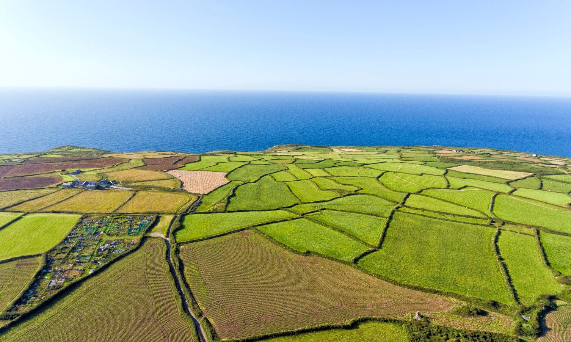 Aerial view of patchwork farm fields running to the sea on the Cornish coast