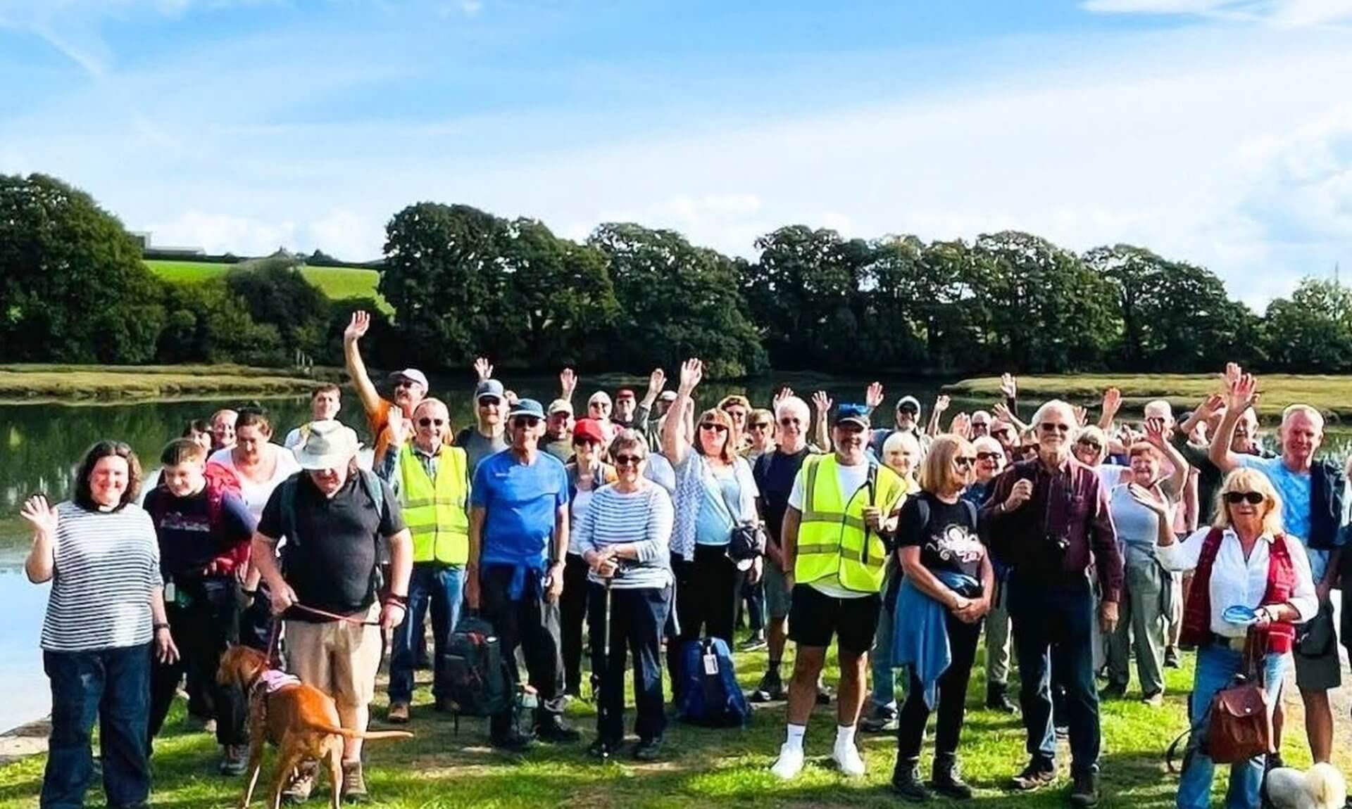 Walkers waving beside the water during Beating the Bounds in Saltash