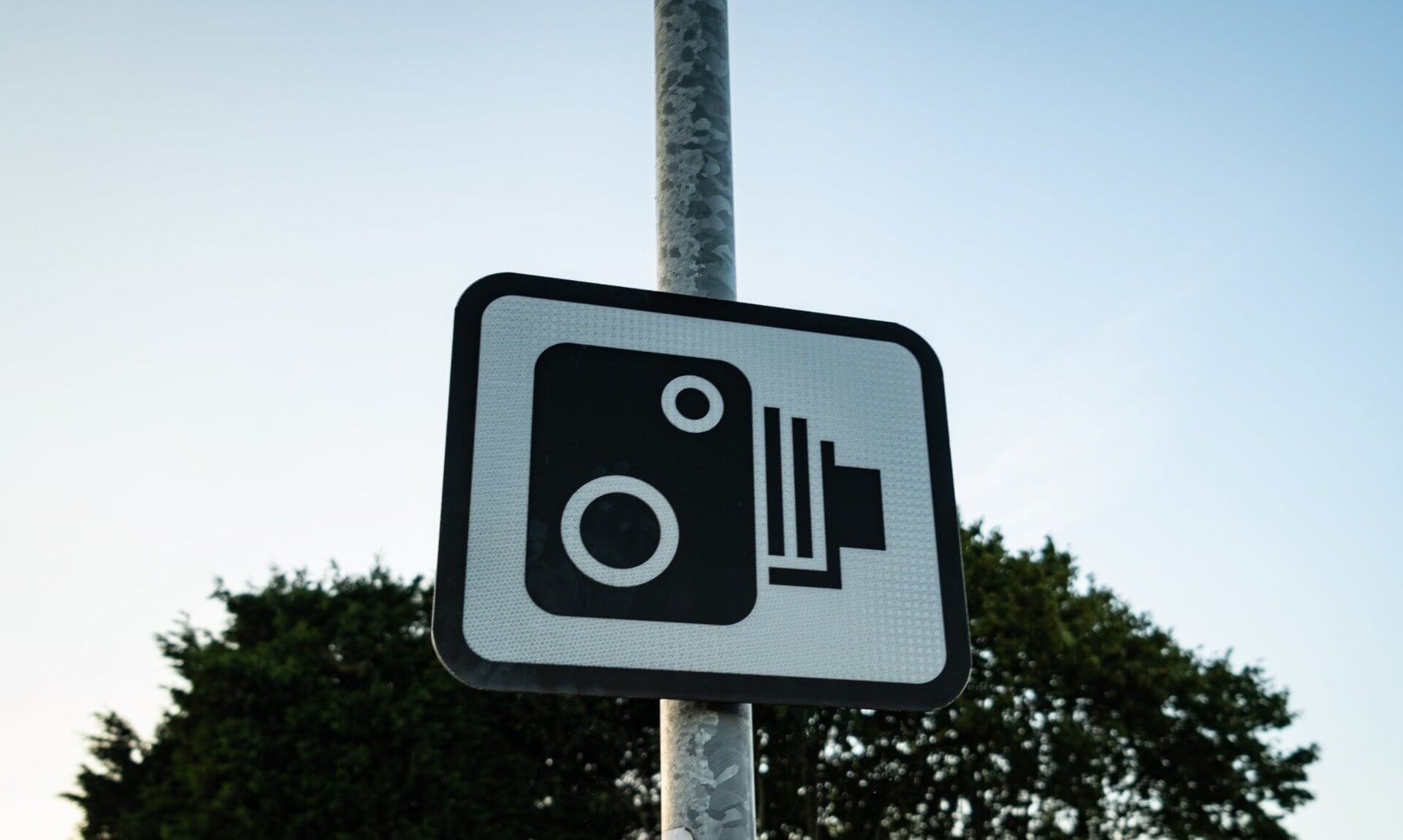 Speed camera warning sign on a pole