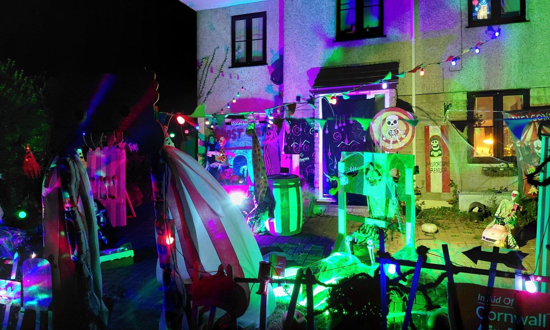 Halloween circus display lit in neon colours outside a house in St Day