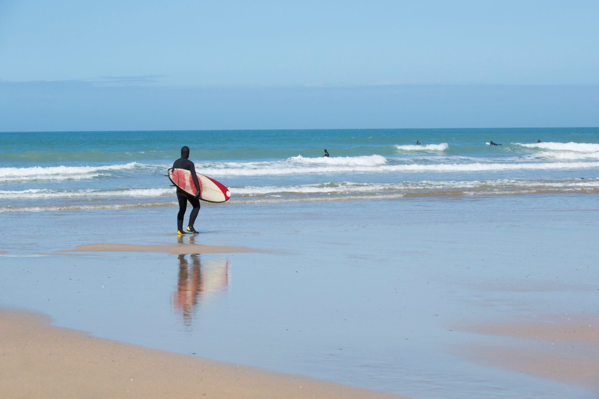 A surfer carrying a board walks towards the sea