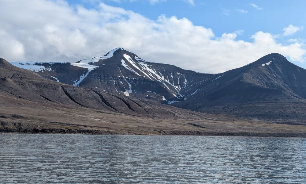 Snow-streaked mountain across the water in Svalbard