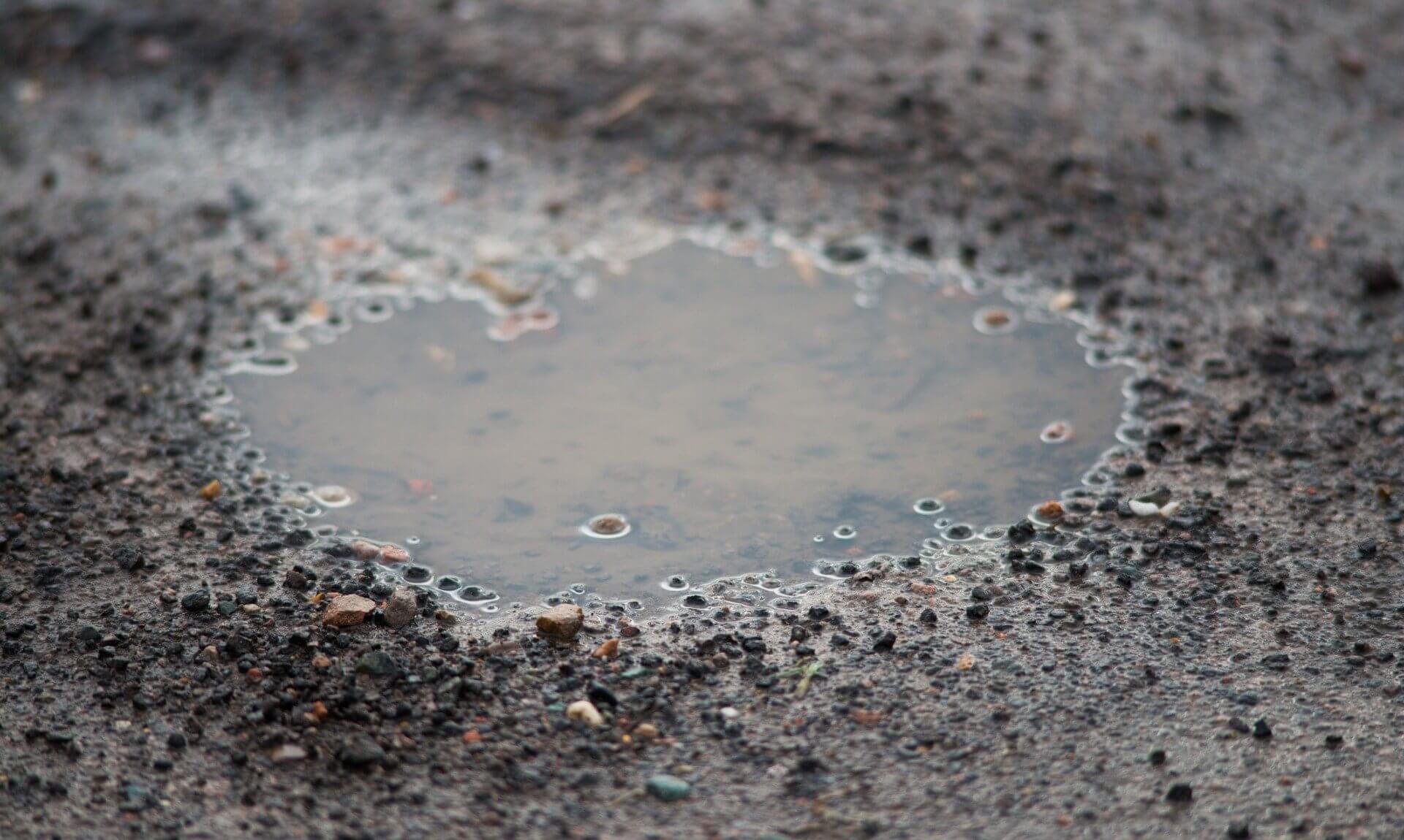 A water-filled pothole in a road surface