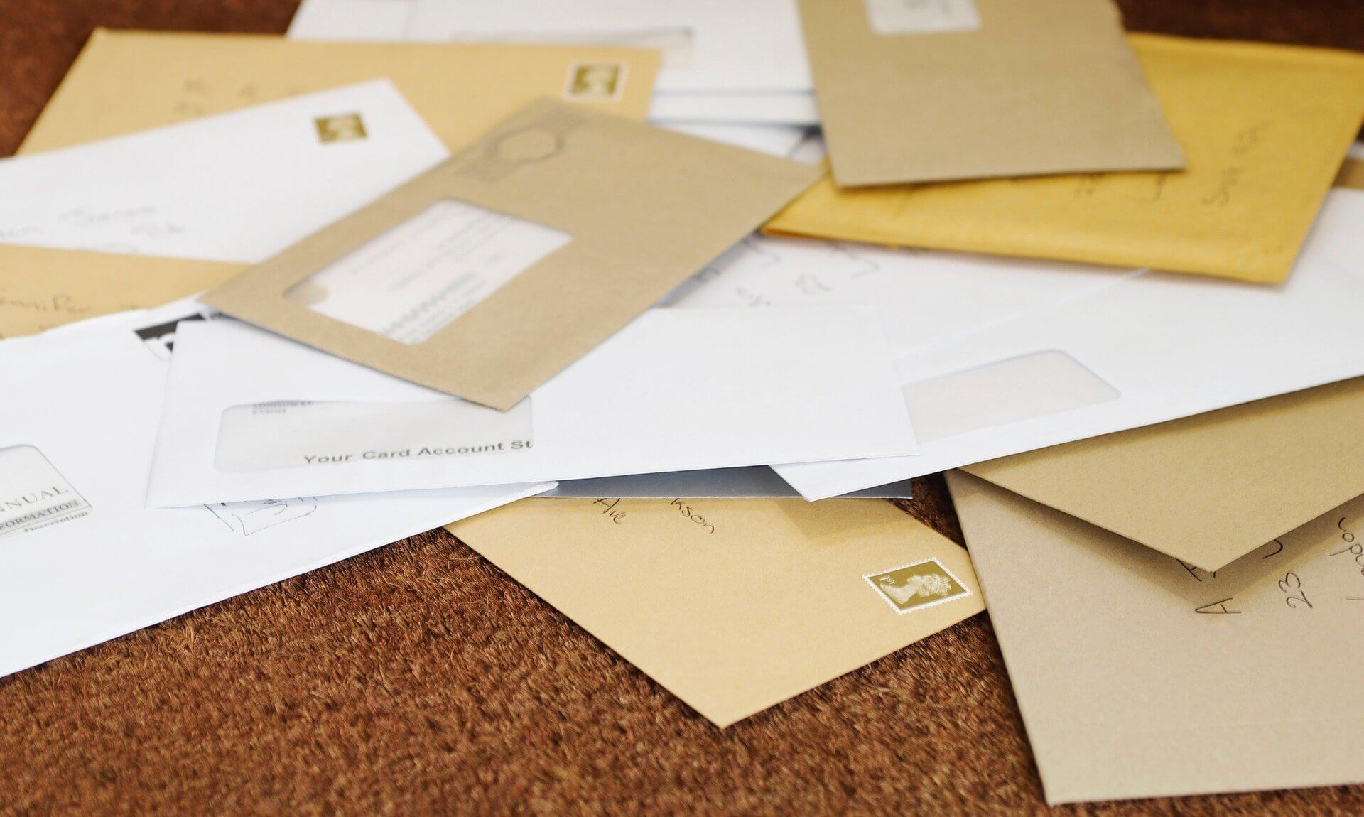 A pile of letters and envelopes on a doormat