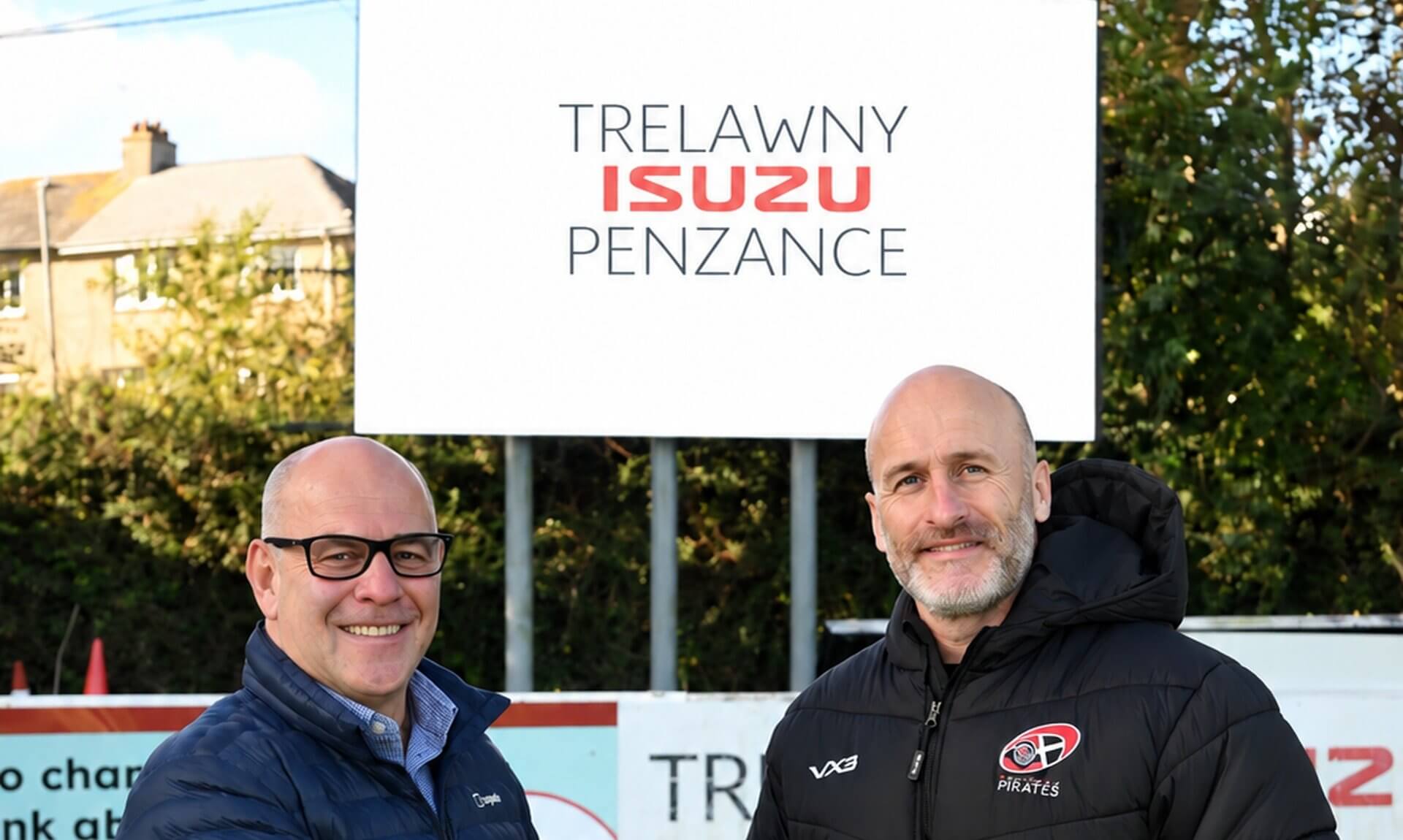 Martin Murrish and Gavin Cattle shaking hands beneath a Trelawny Isuzu Penzance sign