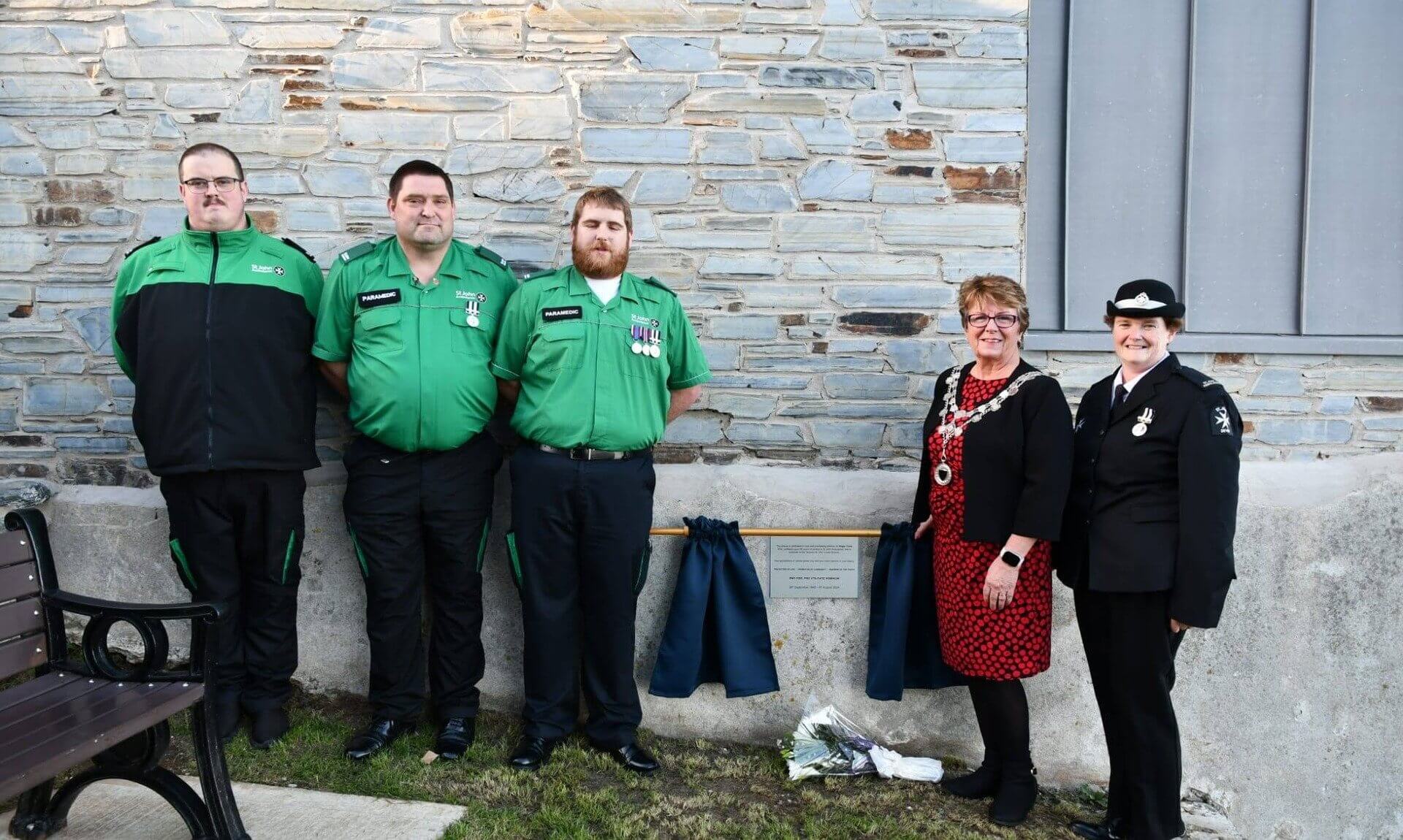 St John Ambulance volunteers and Torpoint Mayor Julie Martin beside the Roger Cook memorial plaque