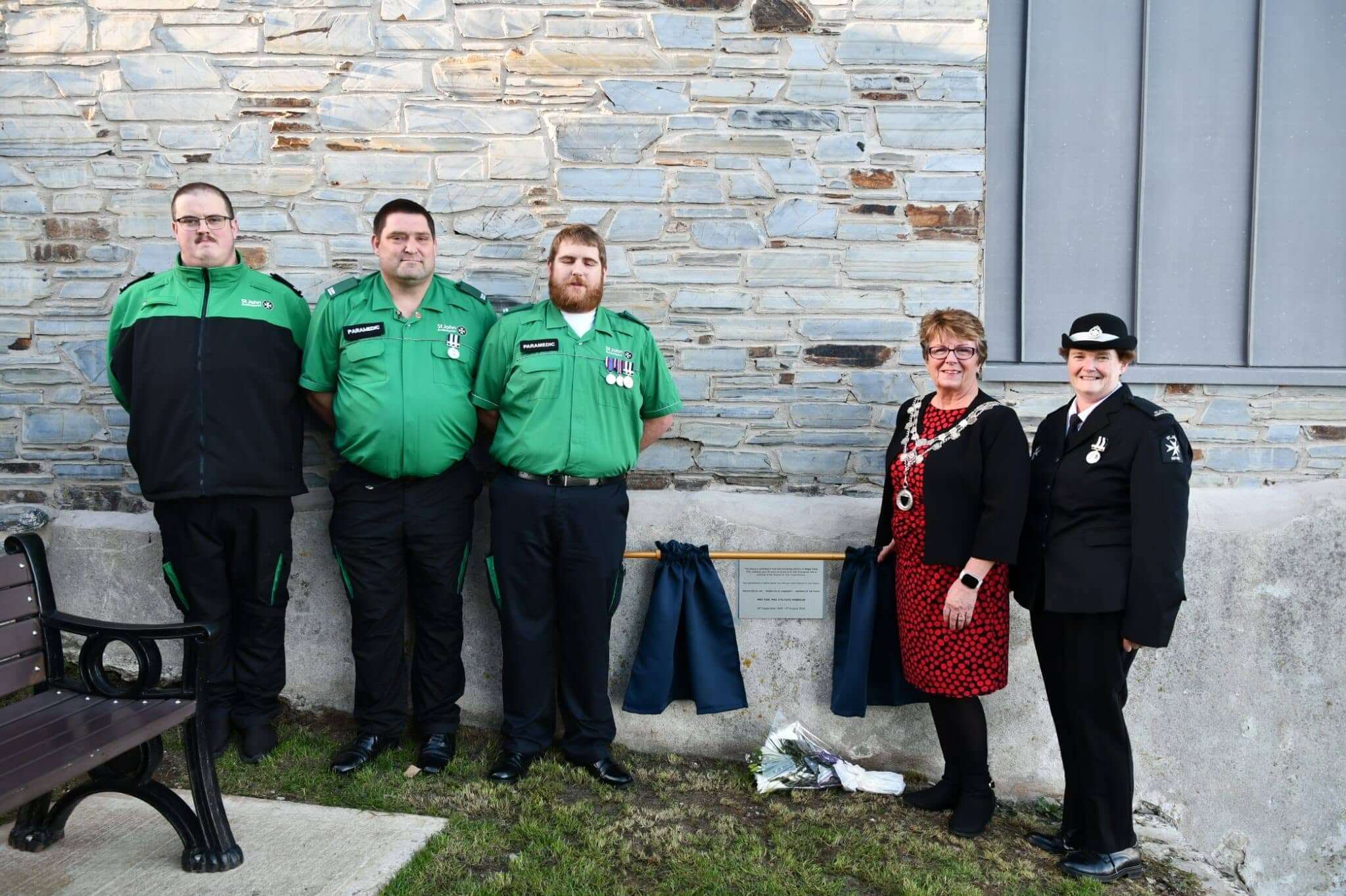 St John Ambulance volunteers and Torpoint Mayor Julie Martin beside the Roger Cook memorial plaque
