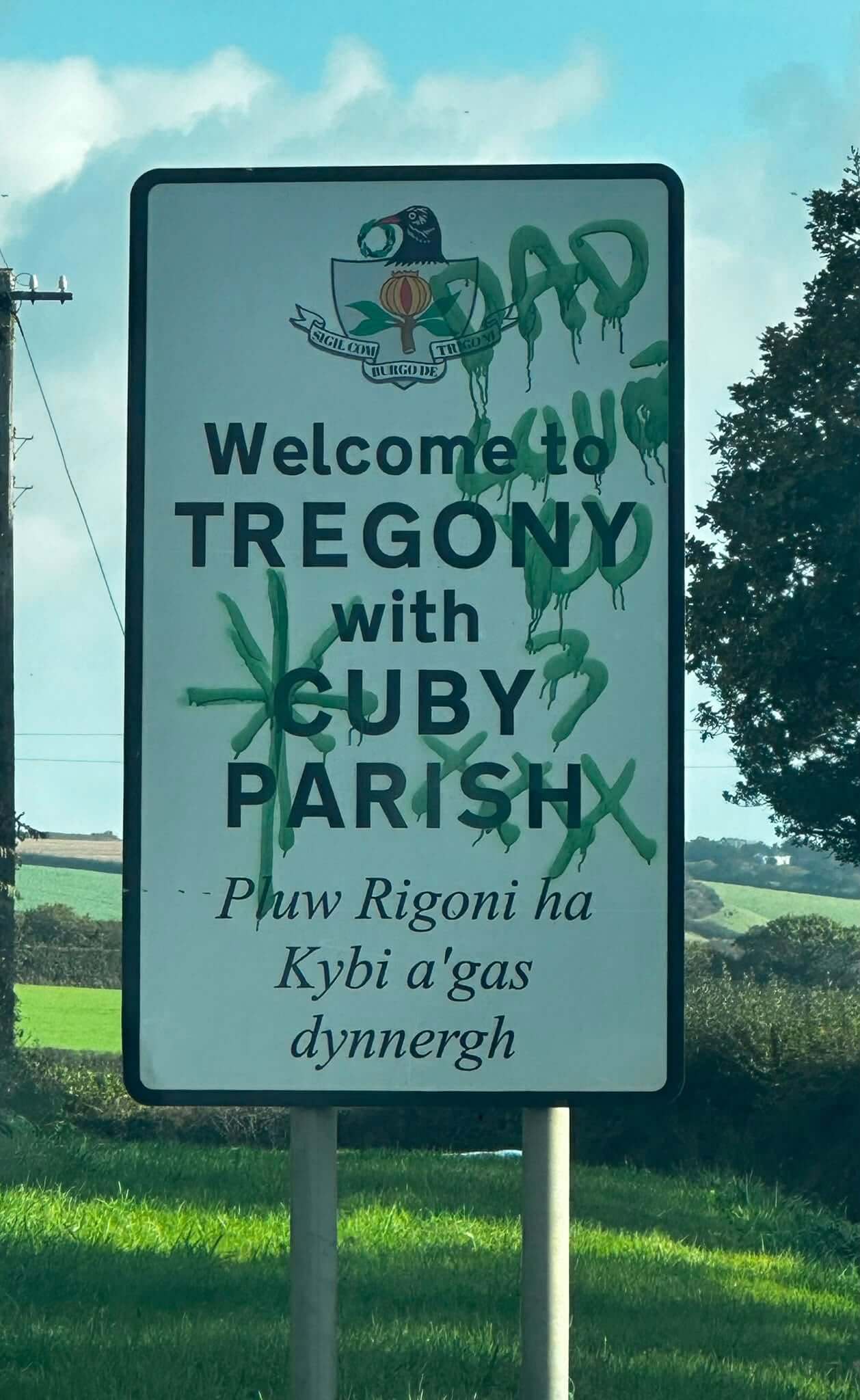 Green graffiti sprayed across the Welcome to Tregony with Cuby Parish road sign