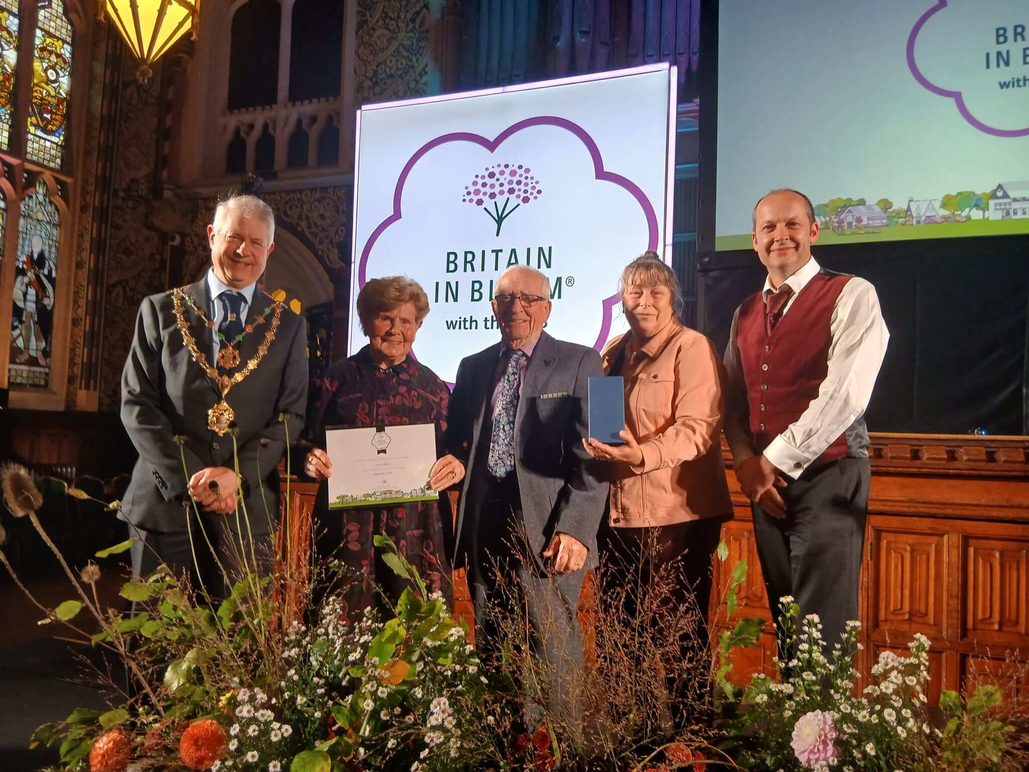 Truro's representatives on stage at the Britain in Bloom 2026 awards holding a certificate and medal