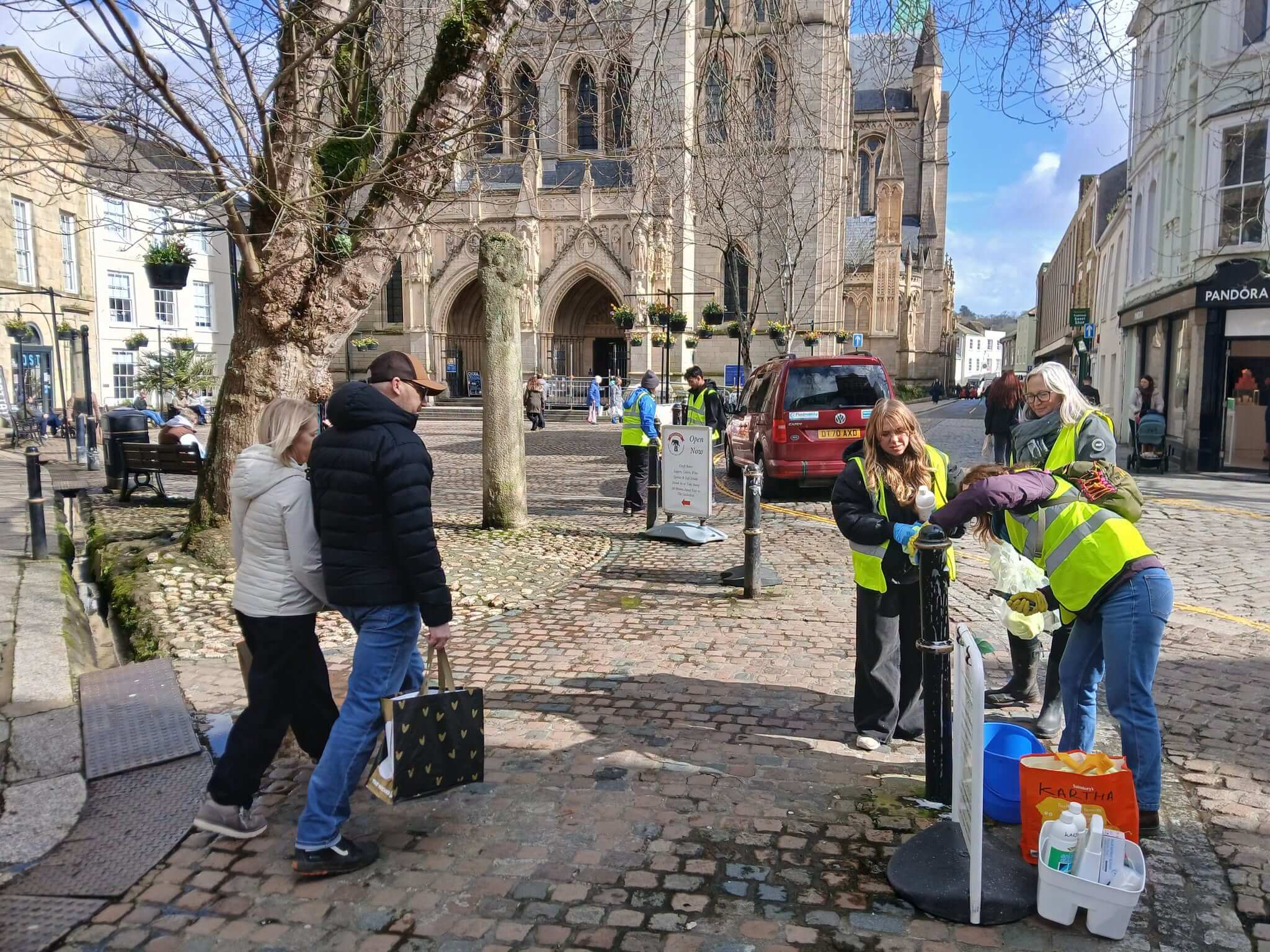 Volunteers in hi vis cleaning street furniture by Truro Cathedral