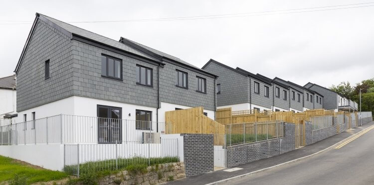 Row of new slate-clad terraced homes on a hillside street