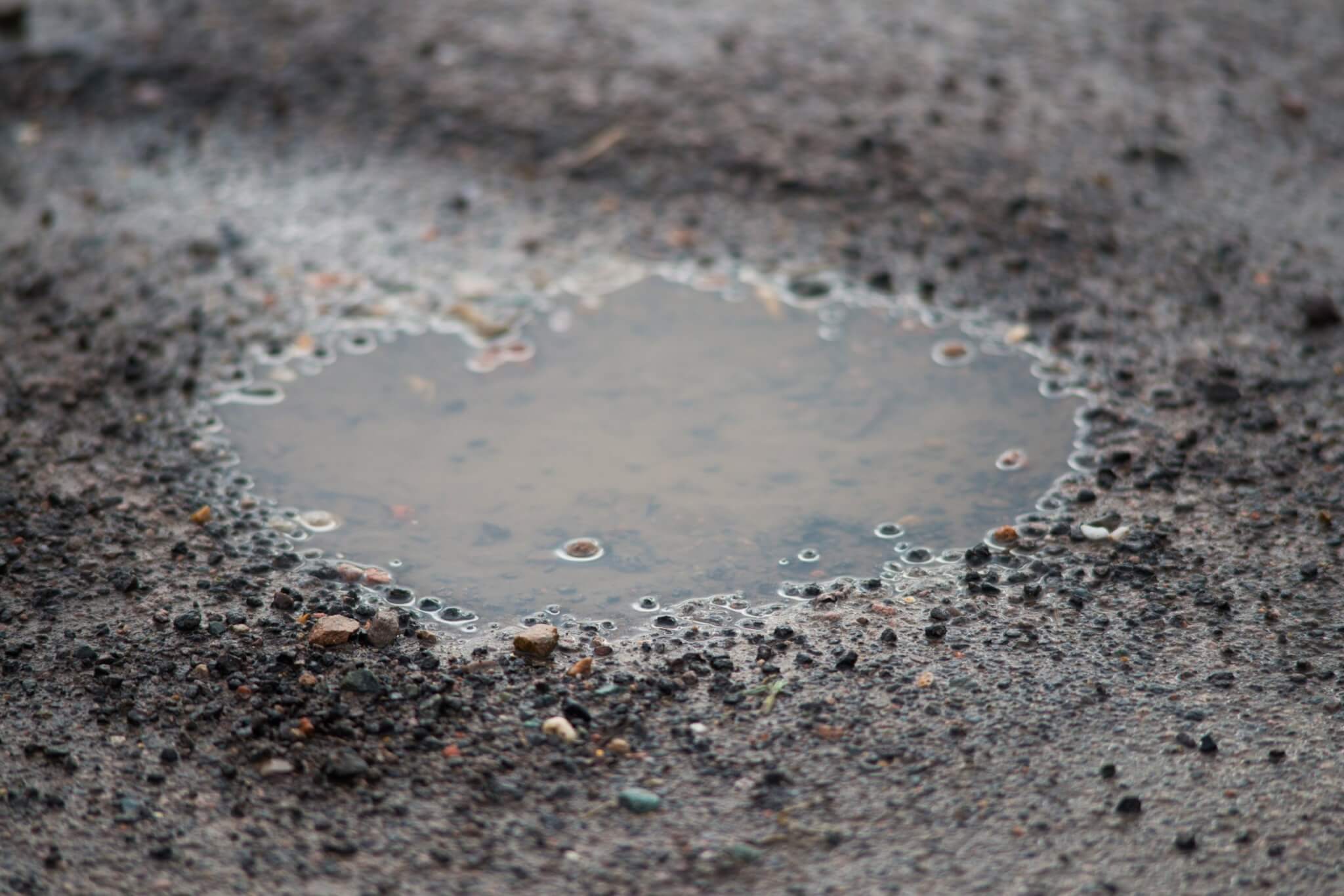A water-filled pothole in a road surface