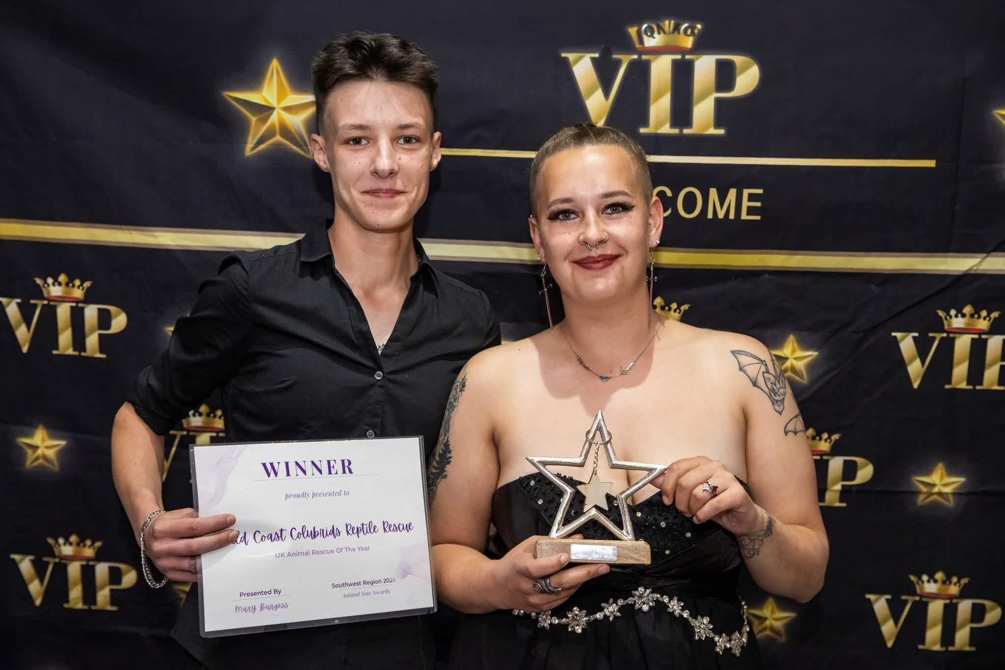 Two people holding a winner's certificate and star trophy