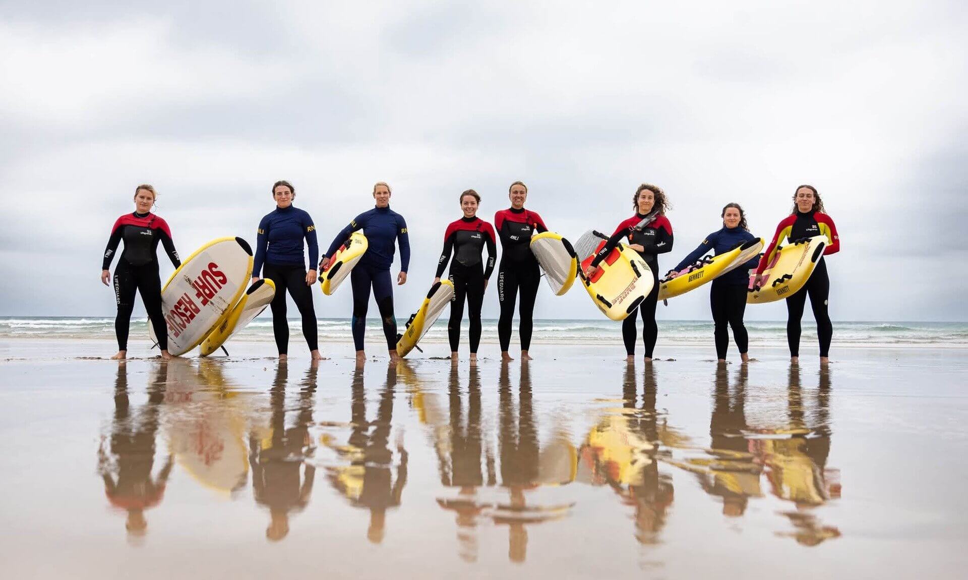 Women lifeguards holding rescue boards on a beach in Newquay