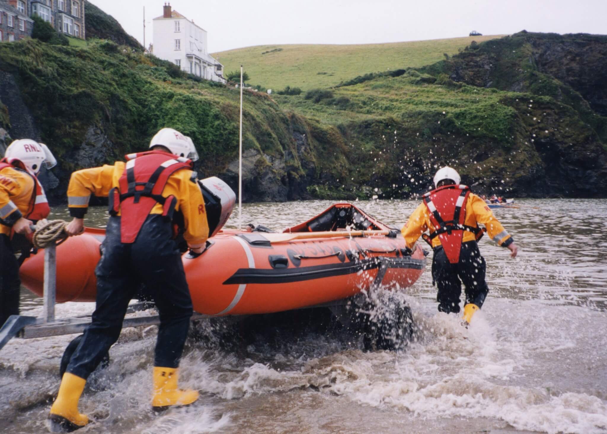 RNLI crew launching a D-class lifeboat into the sea at Port Isaac