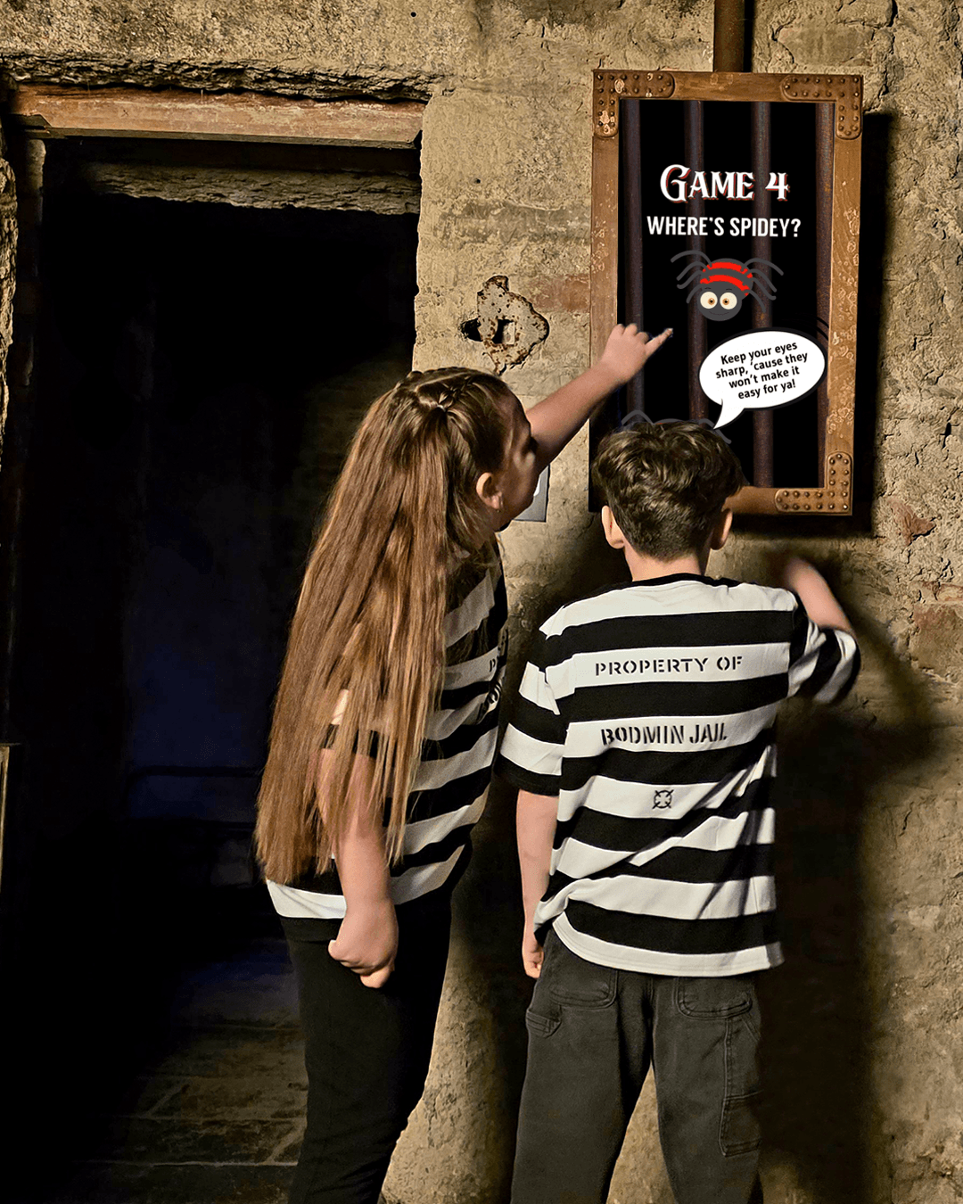 Two children in striped prison tops solving a trail game at Bodmin Jail