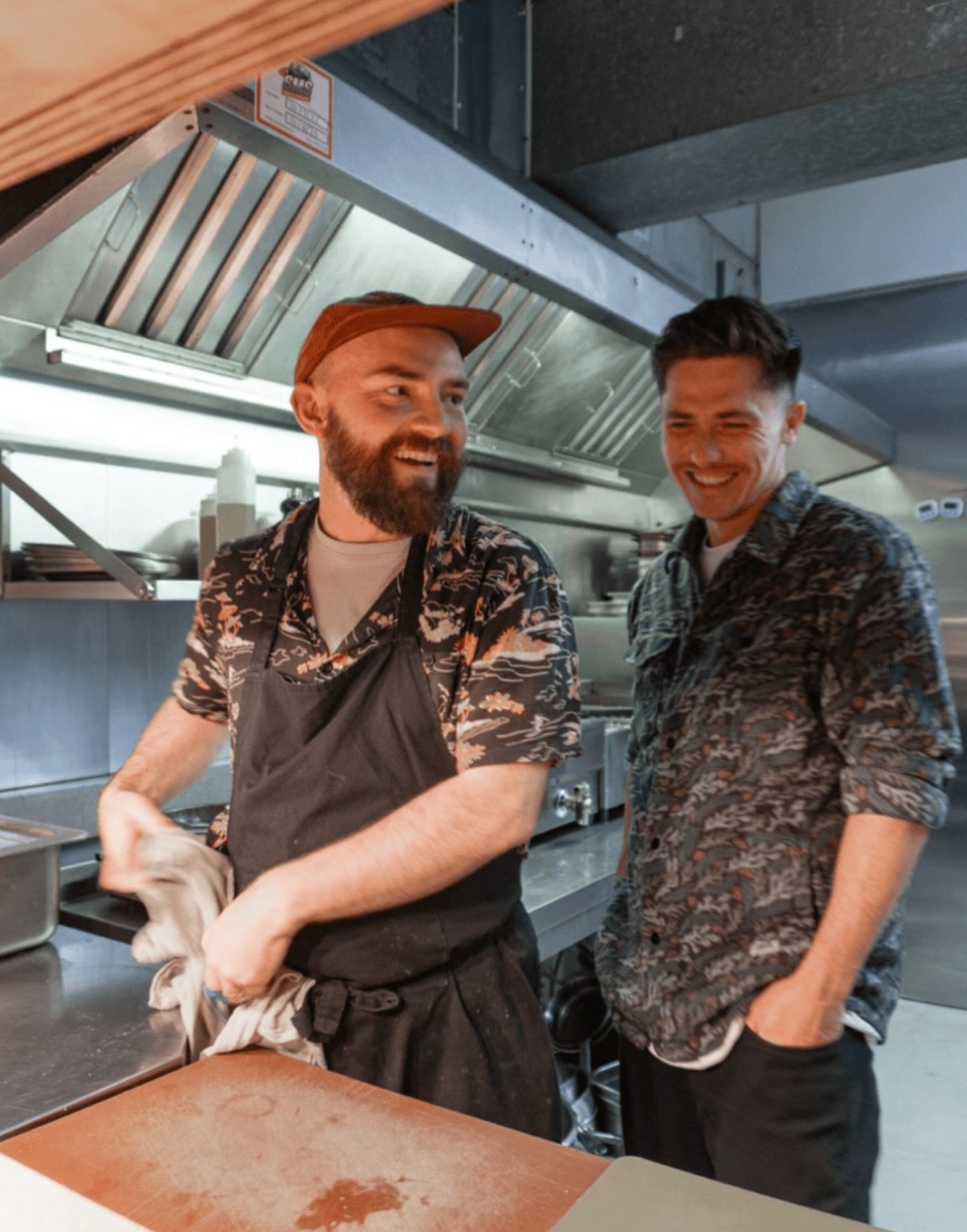 Two men laughing together in a restaurant kitchen