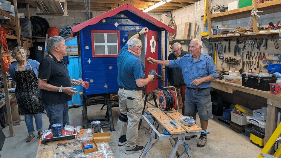 Looe Shedders volunteers working on a painted playhouse in their workshop
