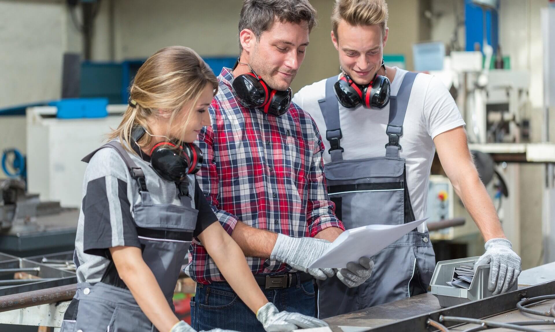 Young apprentices in a workshop looking over plans with a supervisor