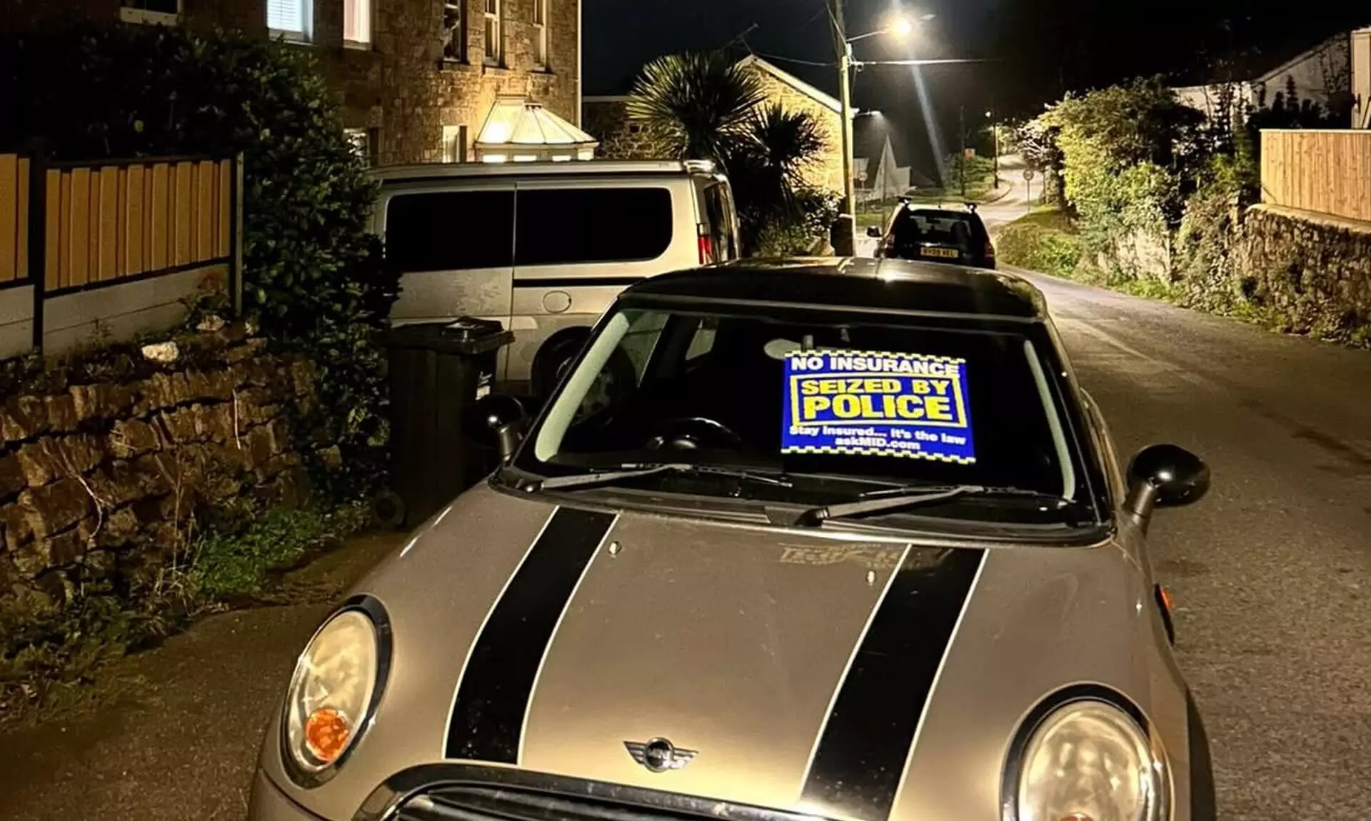 Mini seized by police with a police seizure notice in its windscreen on a West Cornwall street at night