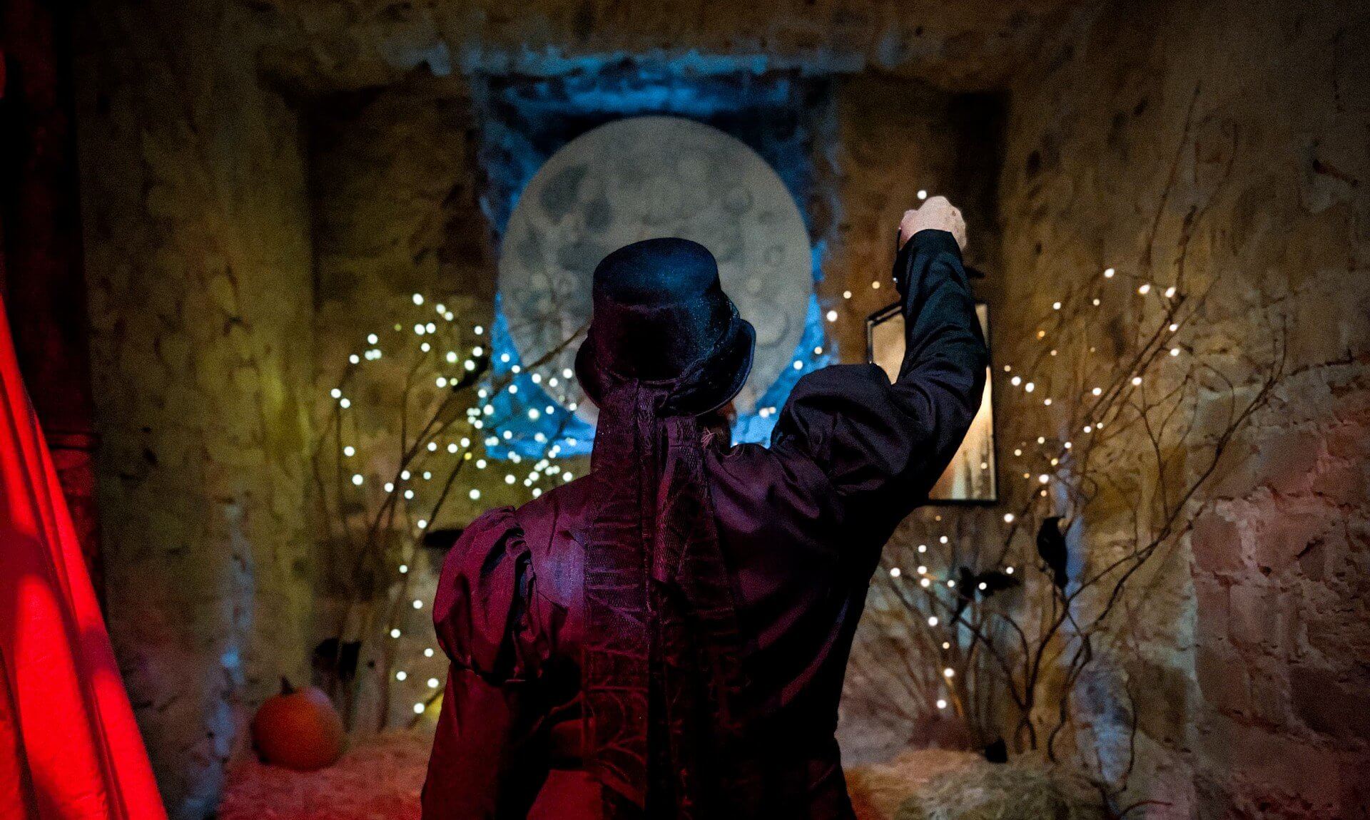 Costumed guide raising a lantern beneath a full moon display at Bodmin Jail