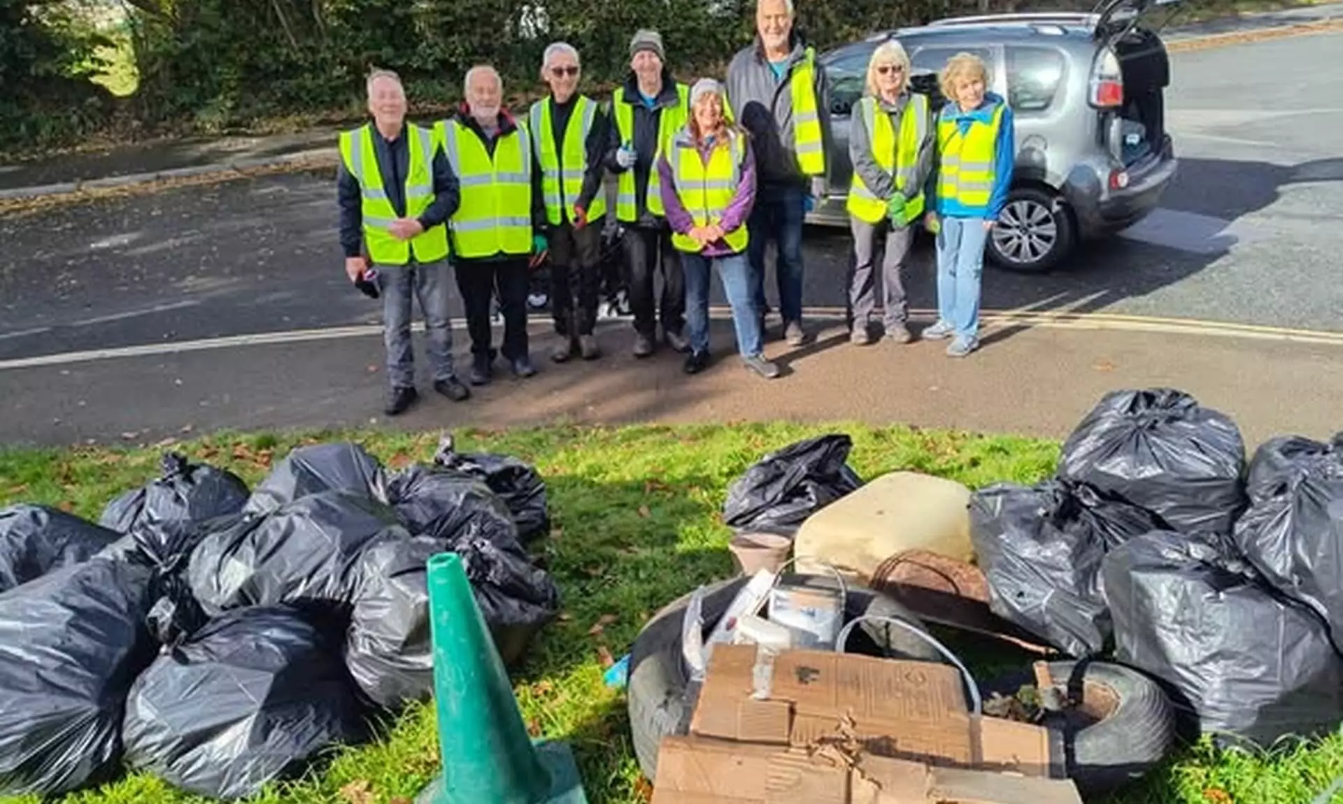 Bodmin Tidy it Team volunteers in hi-vis vests standing behind bags of collected rubbish