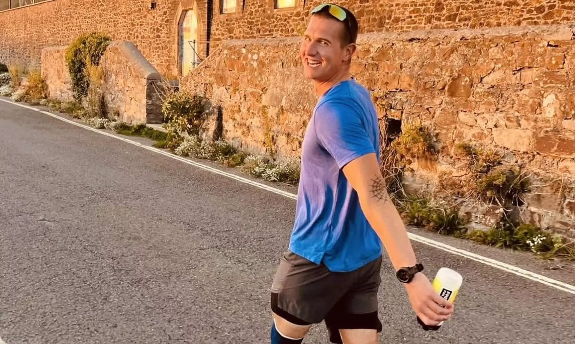 Runner in a blue t-shirt smiling during the 25-hour challenge in Bude