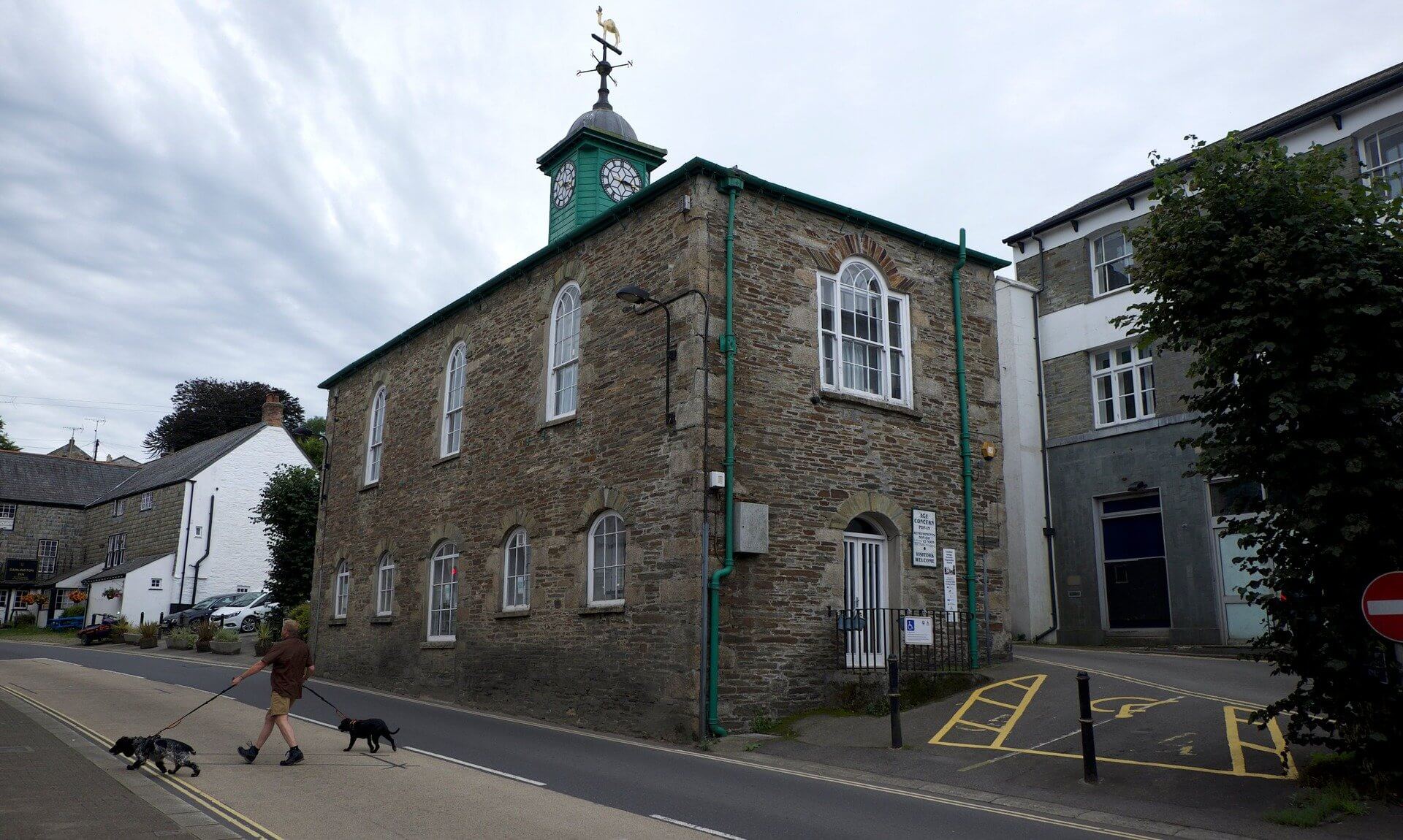 Stone building with a green clock tower and weathervane in Camelford