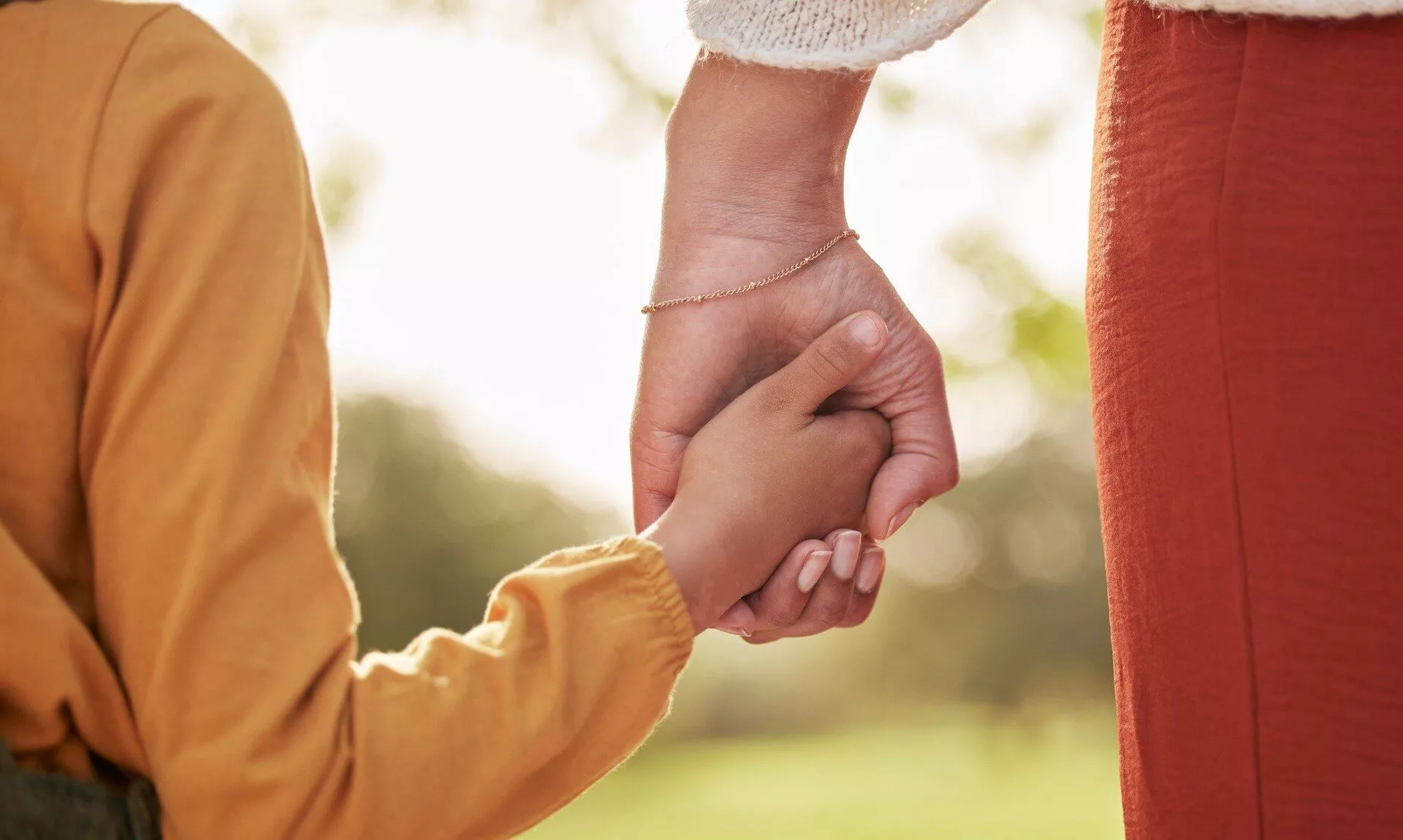 Parent holding a child's hand outdoors